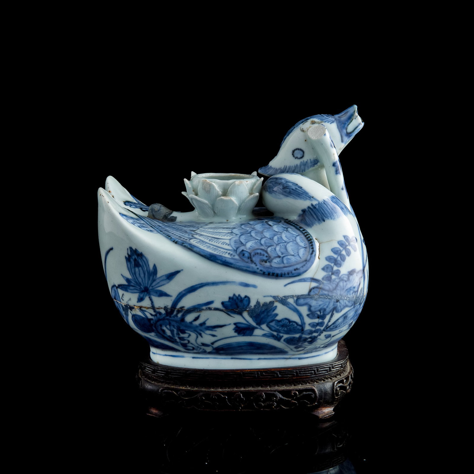A Chinese blue and white mandarin 'duck'-form flower vase, Ming dynasty: A Chinese blue and white mandarin 'duck'-form flower vase Ming dynasty Two mandarin ducks are placed side by side, with one's head tucked underneath the other’s. Sold with one associated hardwood st