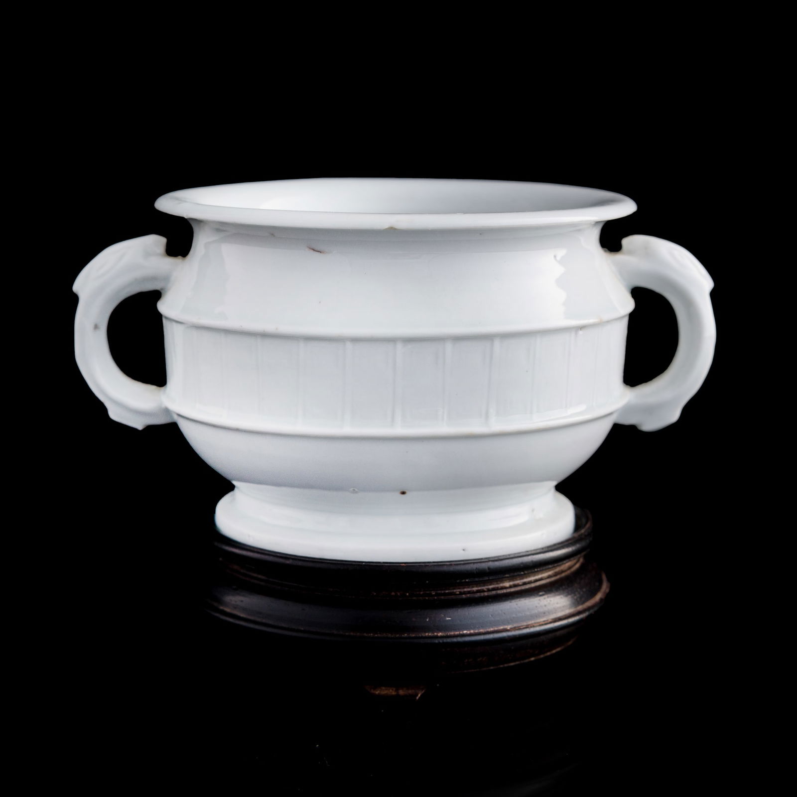 A Chinese blanc-de-chine double-handle censer, 18th century: A Chinese blanc-de-chine double-handle censer 18th century With two old stickers to body and underside. Sold with associated hardwood stand. H: 3, W: 5 3/4, D: 4 1/8 in. (H: 7.62, W: 14.61, D: 10.48 c