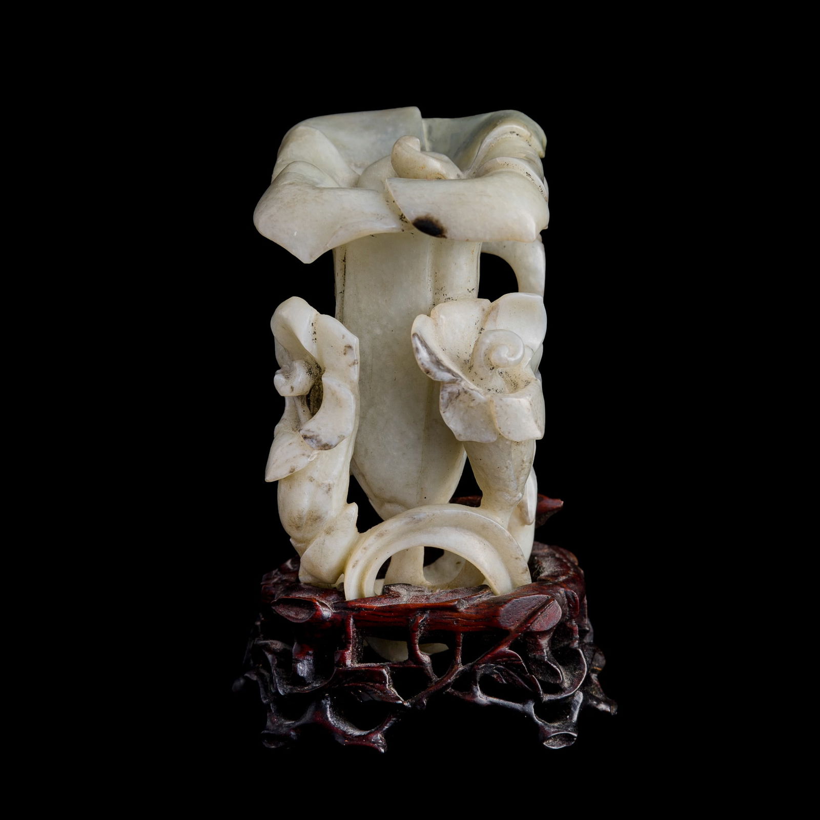 A Chinese jade flower-shaped vase, 18th century: A Chinese jade flower-shaped vase 18th century Sold with associated wooden stand. H: 3 1/2, W: 2, D: 2 3/8 in. (H: 8.89, W: 5.08, D: 6.03 cm. (vase, approximately)) From the collection of Dr. Clinksda