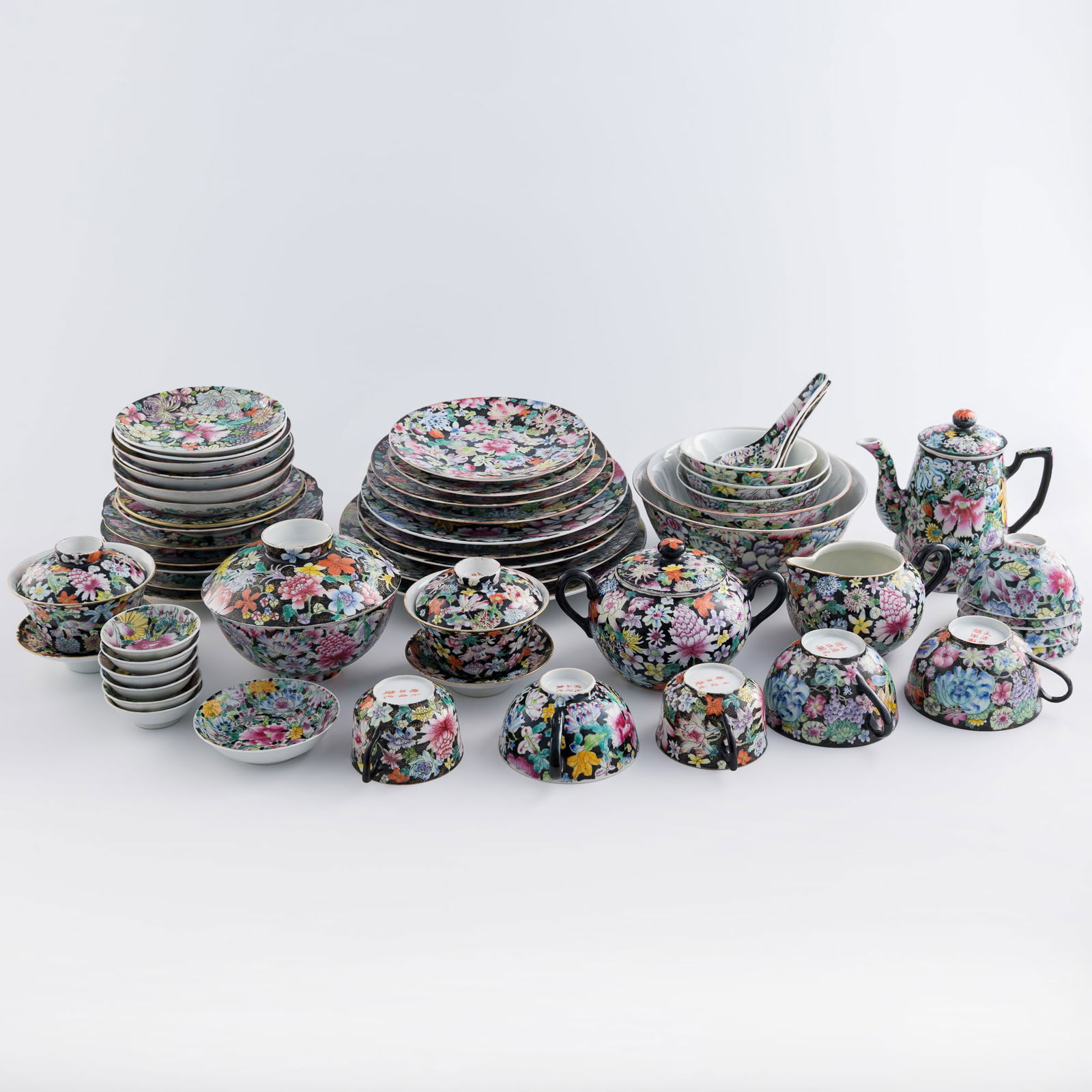 Fifty-three-piece Chinese black-ground 'mille fleur' dinnerware set, Republic period: Fifty-three-piece Chinese black-ground 'mille fleur' dinnerware set Republic period Comprising three spoons; five handled teacups; six sauce dishes; nine bowls of various sizes; a sugar bowl and a cre