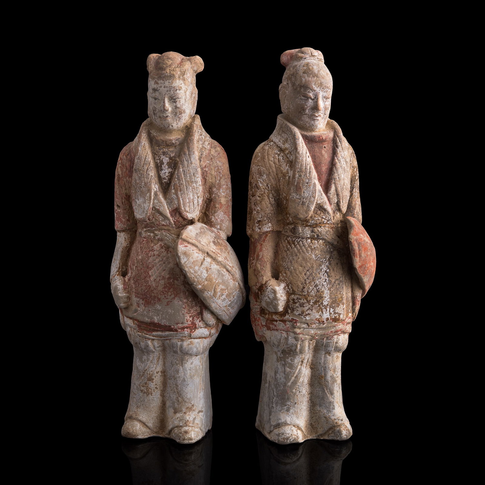 Two Chinese pottery figures, Tang dynasty: Two Chinese pottery figures Tang dynasty Both holding a shield. (2). H: 9 5/8, W: 3 1/8, D: 2 3/4 in. (H: 24.45, W: 7.94, D: 6.99 cm. (each)) Private collection, New York City, New York.