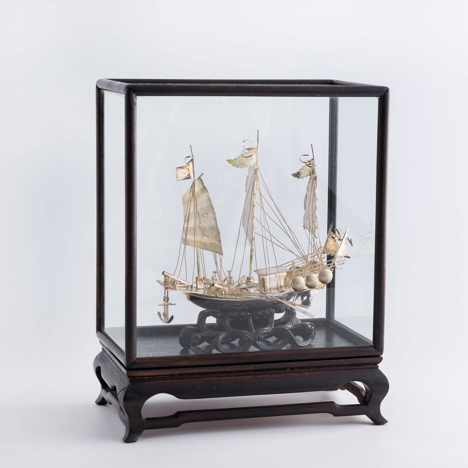 A Chinese silver sail boat, late 19th century: A Chinese silver sail boat late 19th century Sold with an associated wood base and a glass-covered wood frame. H: 7 1/2, W: 7 1/2, D: 4 in. (H: 19.05, W: 19.05, D: 10.16 cm. (boat+stand)) Weight: 213.