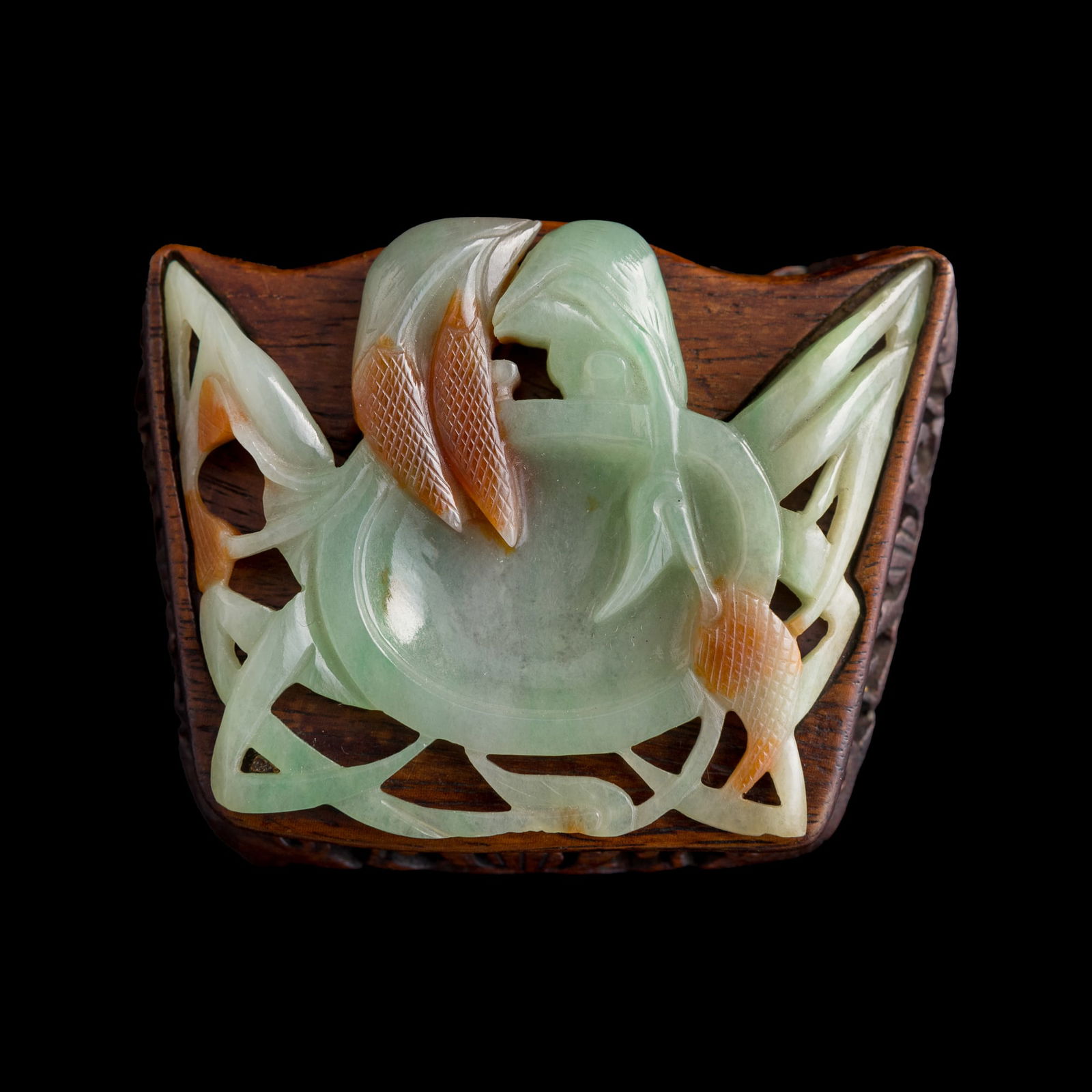 A Chinese jadeite twin-bird ink dish, 19th century: A Chinese jadeite twin-bird ink dish 19th century Carved as two jadeite birds facing each other and merging into a single abstract form. Sold with associated wooden stand. H: 3/8, W: 2 3/4, D: 2 1/8 i