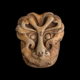 A Chinese chicken bone jade carving of a mask, Tang dynasty or earlier