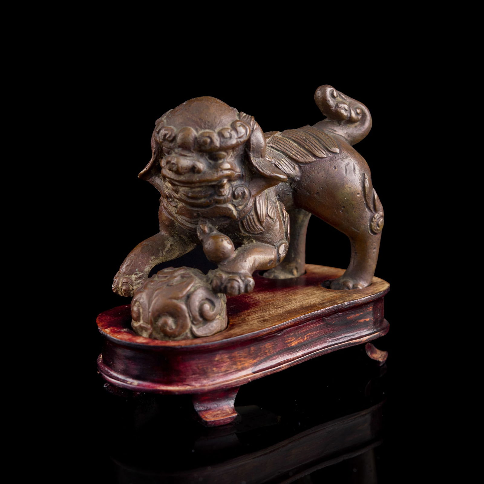 A Chinese copper-alloy lion, 18th century or earlier: A Chinese copper-alloy lion 18th century or earlier Sold with associated hardwood stand. H: 2 3/4, W: 1 7/8, D: 3 3/4 in. (H: 7, W: 4.8, D: 9.5 cm. (lion)) Weight: 356.3 g (lion) From Mrs. Budow of Ma