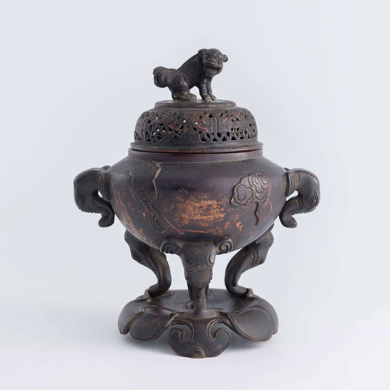 A Chinese bronze tripod censer, 19th century: A Chinese bronze tripod censer19th centuryDecorated with a pair of elephant-head handles and supported on three feet, the body is cast with scattered auspicious clouds. It is offered together with a