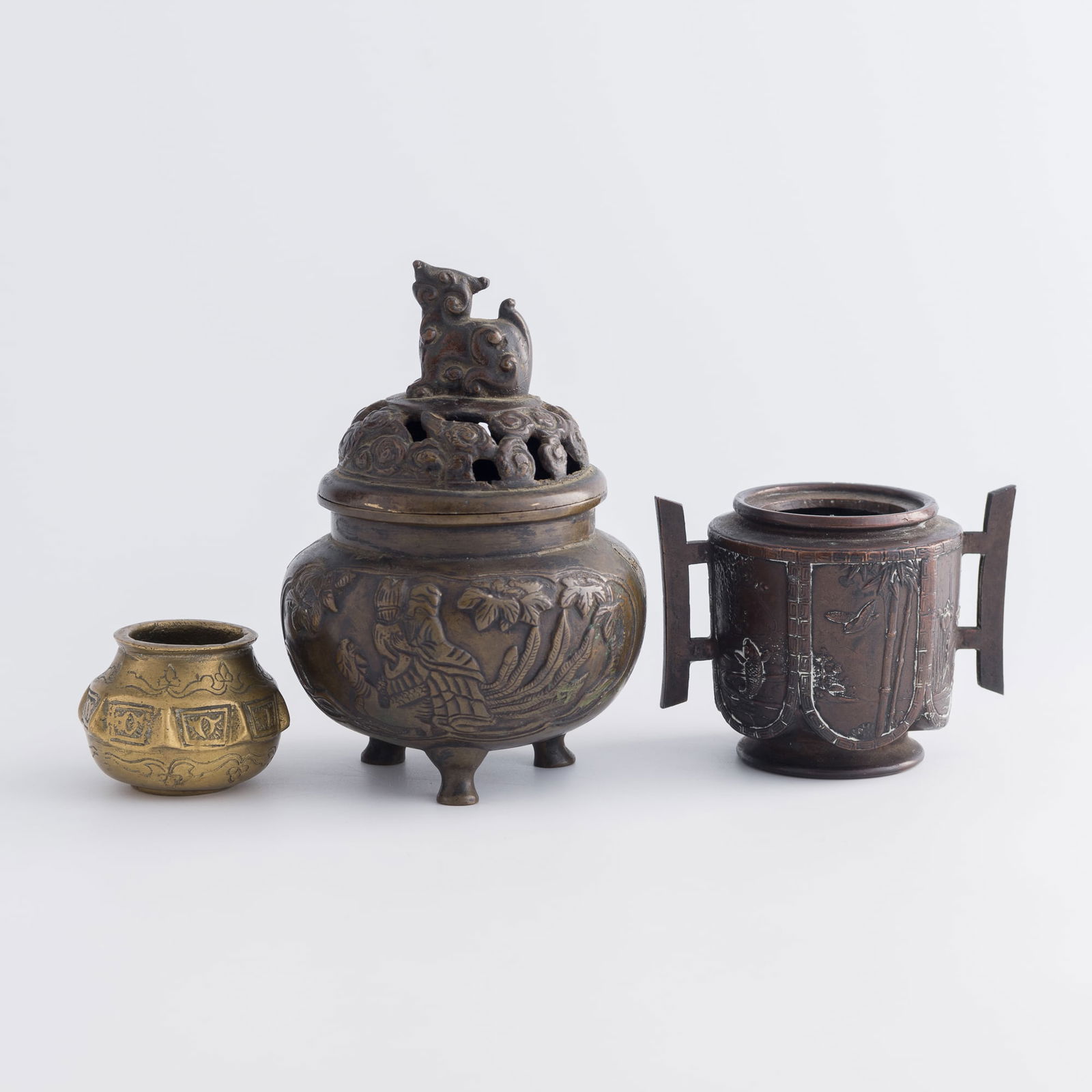 Three Chinese censers, 19th century: Three Chinese censers19th centuryComprising a bronze tripod censer with a beast finial, a bronze censer with two handles, and a brass censer with raised ridges. (3)H: 6, Dia: 4 1/8 in. (H: 15.2, Dia: