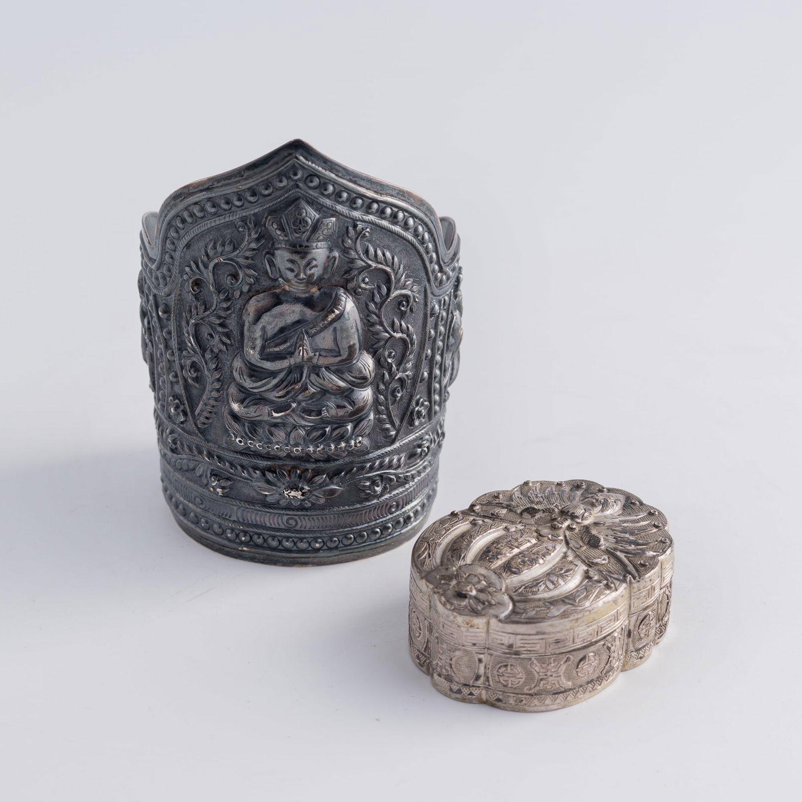 A Chinese silver ornamental arm guard and a silver box, 19th century: A Chinese silver ornamental arm guard and a silver box19th centuryThe arm guard with "CHINA" and "SILVER" marks to verso, and the box with "zu wen" and "Yutai" marks to underside. (2).H: 4, W: 2 3/4,