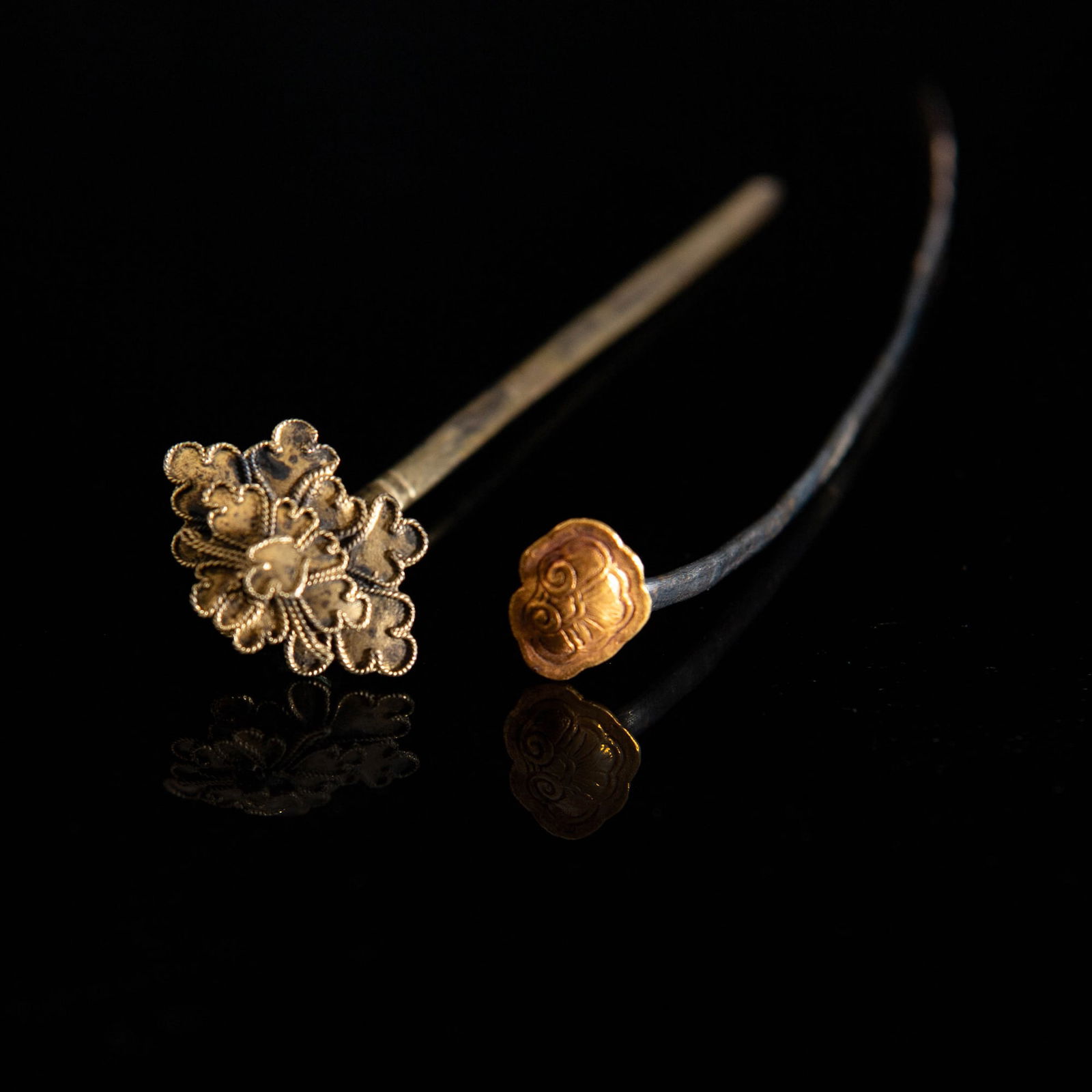 Two Chinese hairpins, 18th/19th century: Two Chinese hairpins18th/19th centuryComprising one marked pin with a marked golden ruyi head; and a metal pin with three-tiered flower decoration. (2)L: 5 3/4 in. (L: 14.6 cm. (longest))Mr.