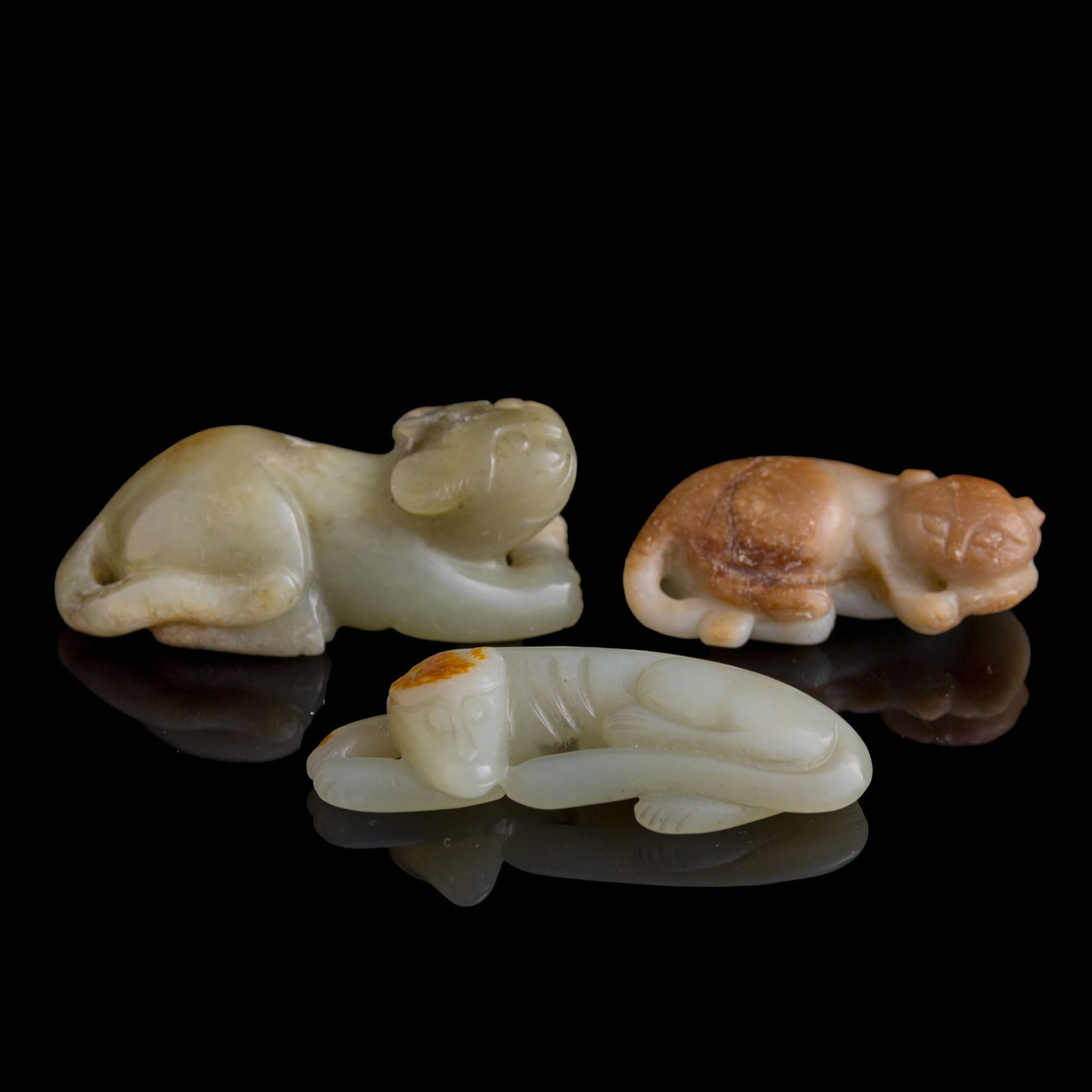 Three Chinese jade carvings of recumbent beasts, Ming/Qing dynasty: Three Chinese jade carvings of recumbent beasts Ming/Qing dynasty Two with natural inclusions throughout, and the third showing small areas of yellow russet. (3). H: 7/8, W: 2 1/2, D: 1 1/4 in. (H: 2.