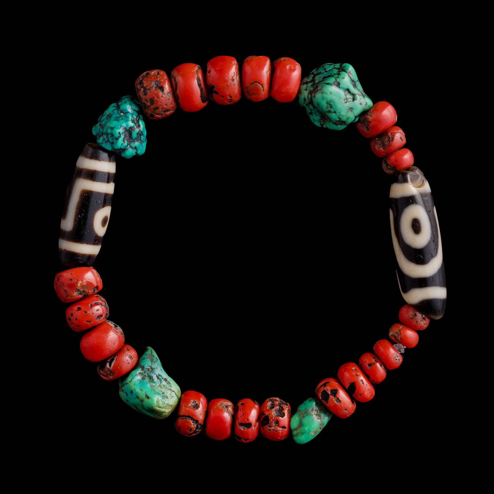 A Chinese bracelet with Dzi bead, coral and turquoise, Qing dynasty or earlier: A Chinese bracelet with Dzi bead, coral and turquoise Qing dynasty or earlier Comprising two Dzi beads, four turquoise beads, and twenty-two coral beads. Ext. Dia: 3 7/8, Int. Dia: 2 3/4 in. (Ext. Dia