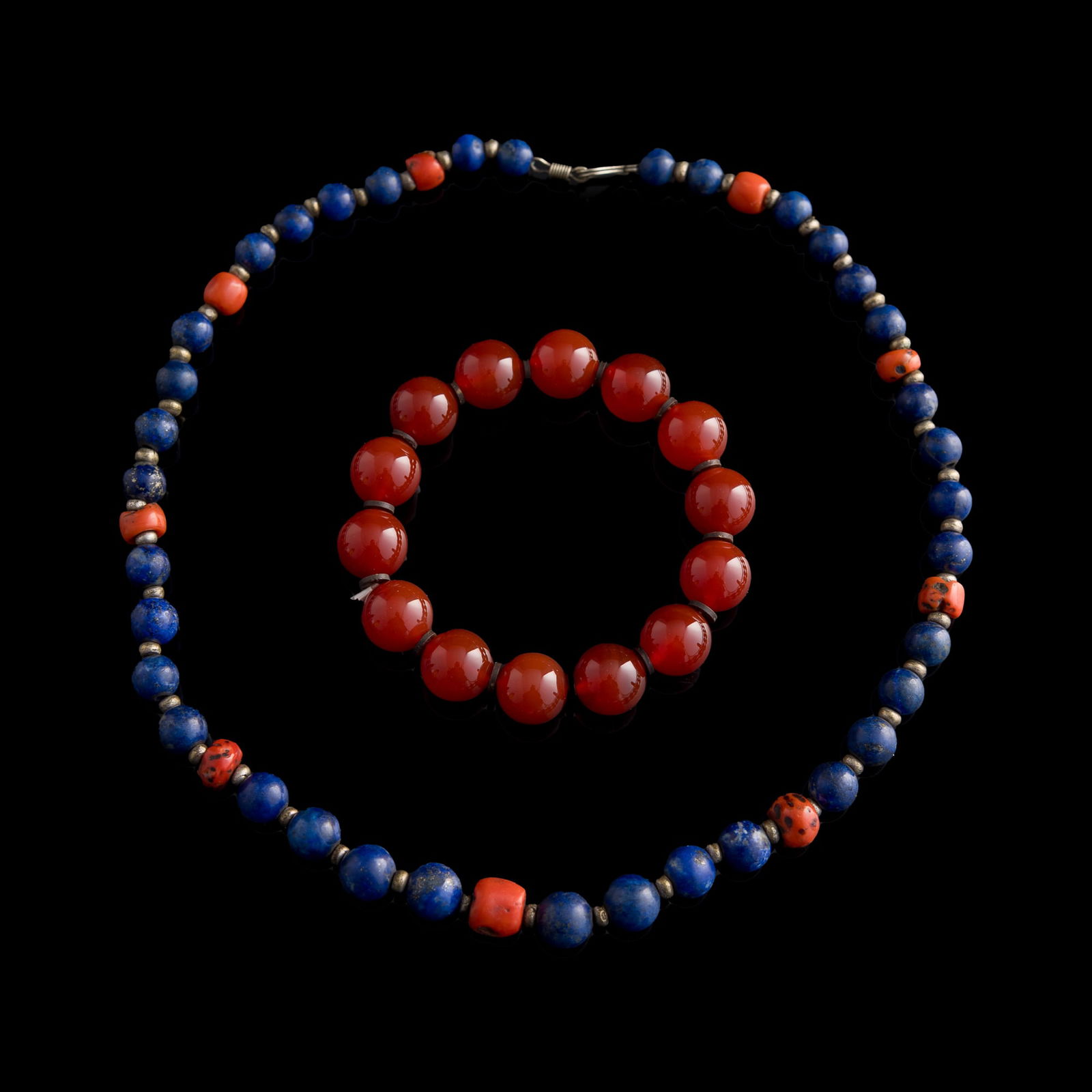 A Chinese lapis necklace and an agate bracelet: A Chinese lapis necklace and an agate bracelet Necklace length: 9 3/4 in. (24.8 cm.), bead dia: 10.61 mm (largest) Bracelet bead dia: 14 mm (each) Necklace weight: 58.46 g Private collection, Mountain