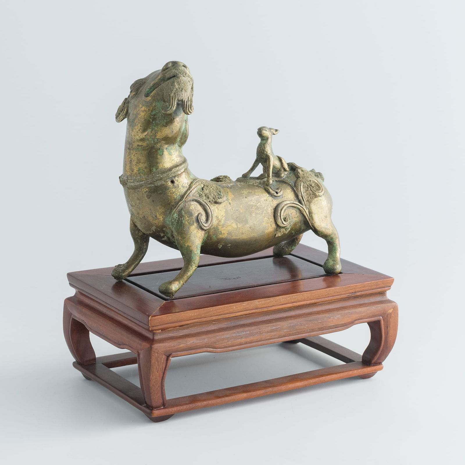 A Chinese gilt-bronze beast, Song dynasty or earlier: A Chinese gilt-bronze beastSong dynasty or earlierSold with associated wooden stand.H: 5 5/8, W: 6, D: 3 in. (H: 14.3, W: 15.2, D: 7.6 cm. (beast))Weight: 863.1 g (beast)From a private collector in