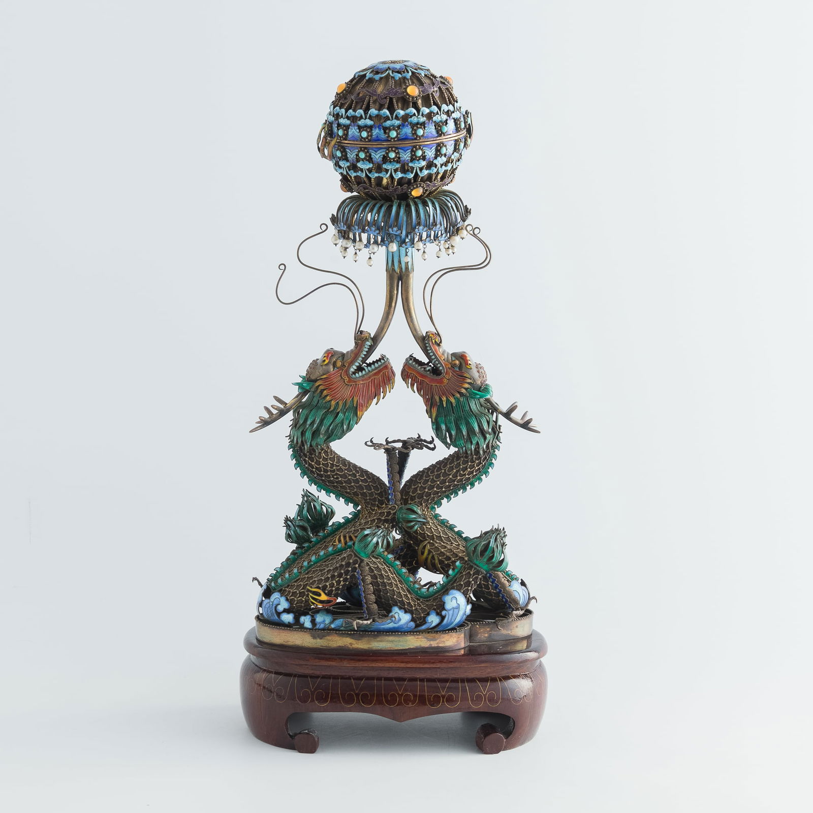 A Chinese silver enamel ornament of dragons chasing pearl, 1950s-1960s: A Chinese silver enamel ornament of dragons chasing pearl1950s-1960sSold with associated wooden stand.H: 17 1/2, W: 7 3/4, D: 5 1/2 in. (H: 44.5, W: 19.7, D: 14 cm. (overall, approximately))From a