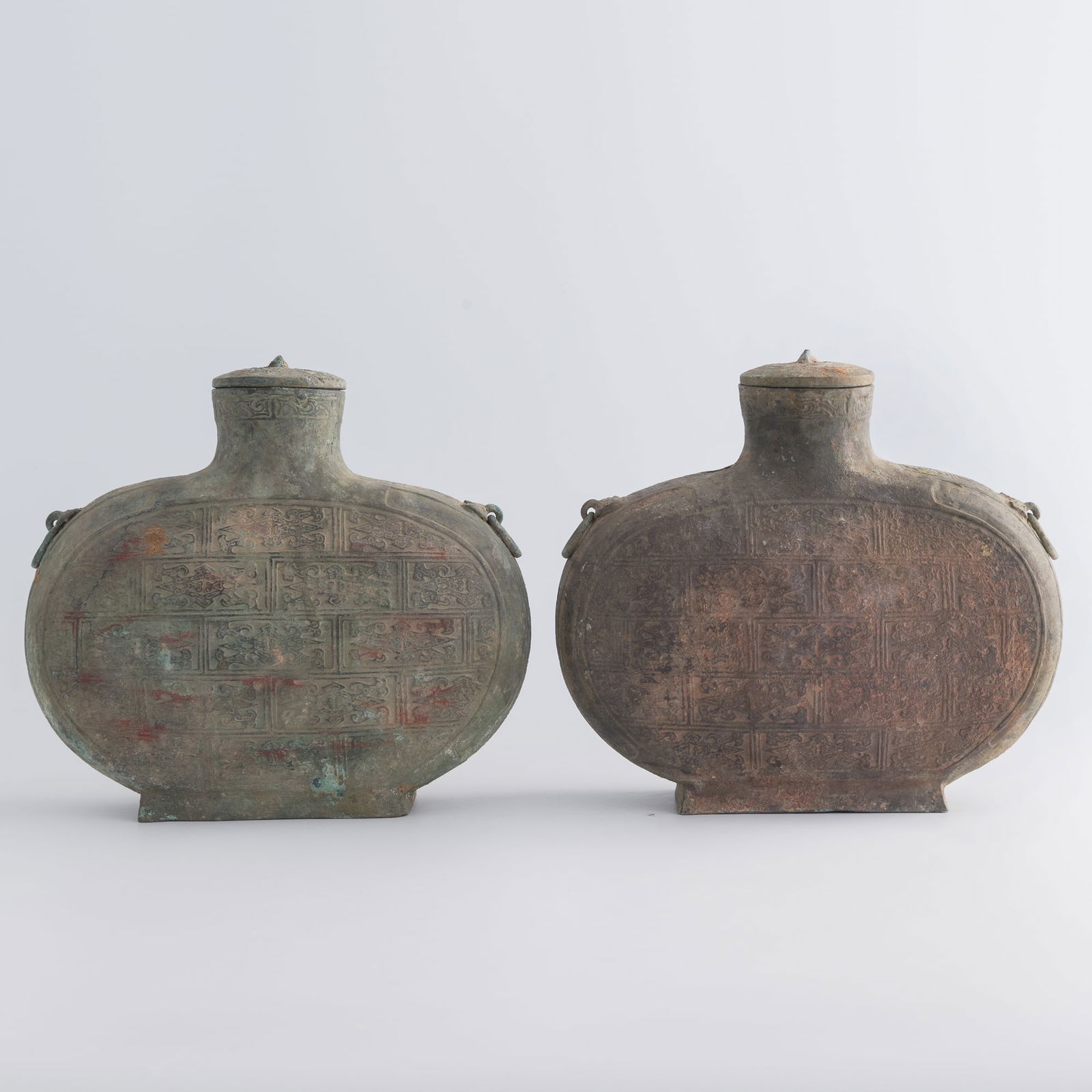 A pair of Chinese lidded bronze cocoon vessels, Warring States period/Western Han dynasty: A pair of Chinese lidded bronze cocoon vessels Warring States period/Western Han dynasty Each vessel has a pair of beast head handles holding engaged rings. They are decorated throughout with stylized