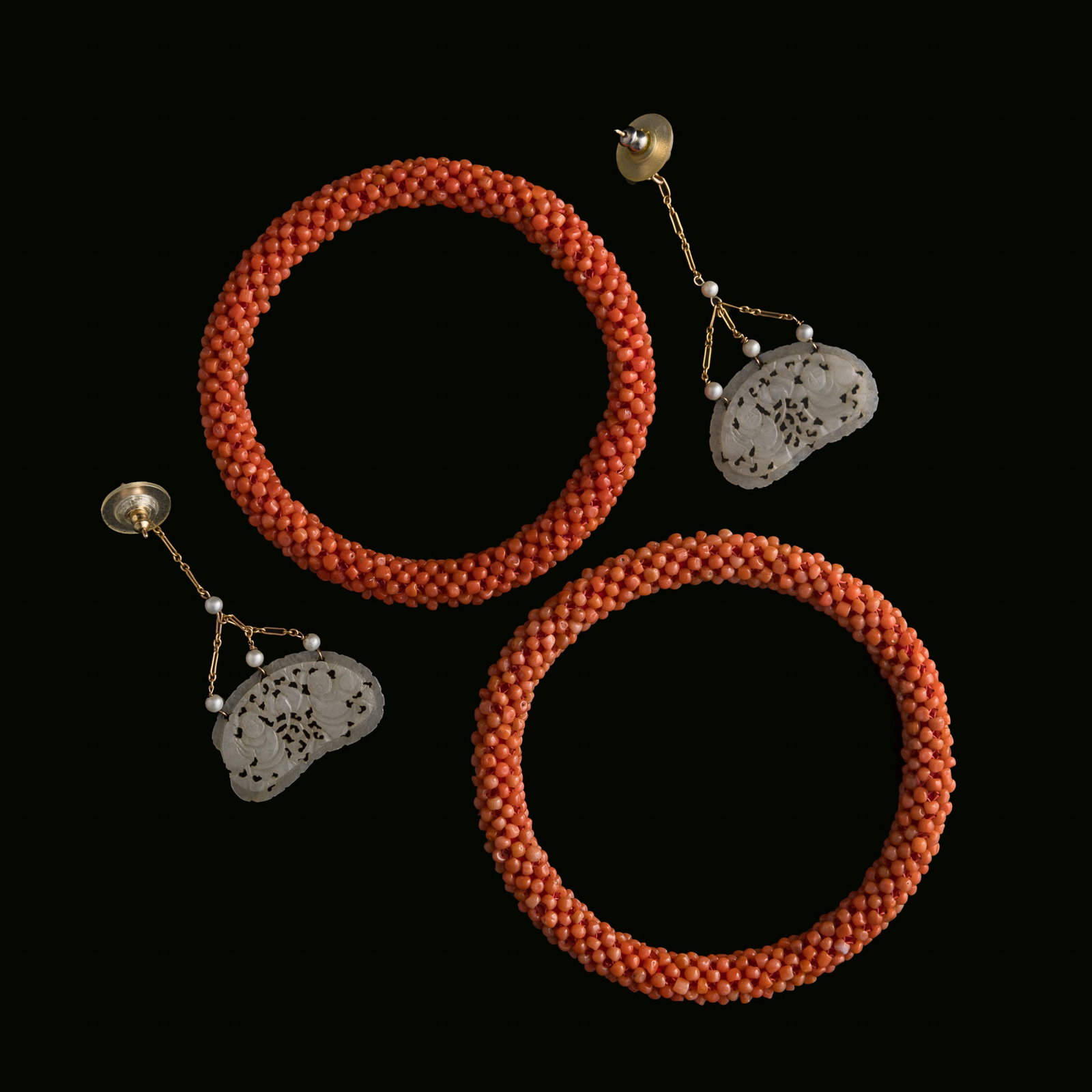 A pair of Chinese coral bead bracelets and a pair of jade earrings, 19th century: A pair of Chinese coral bead bracelets and a pair of jade earrings 19th century Bracelet: Inner Dia: 65.2 mm, D: 7.6 mm Weight: 35.8 g (bracelet, overall) Private collection, Saratoga, California.