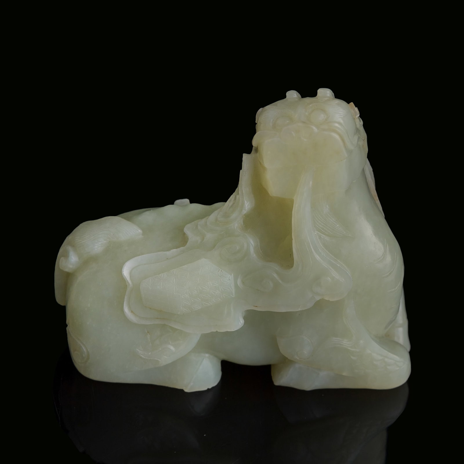 A Chinese jade carving of Pixiu,: A Chinese jade carving of Pixiu Carved as Pixiu, an auspicious beast with double horns, a lion's head and a horse-like body, exhaling a book amid cloud scrolls. H: 3 7/8, W: 4 1/4, D: 2 in. (H: 9.8, W