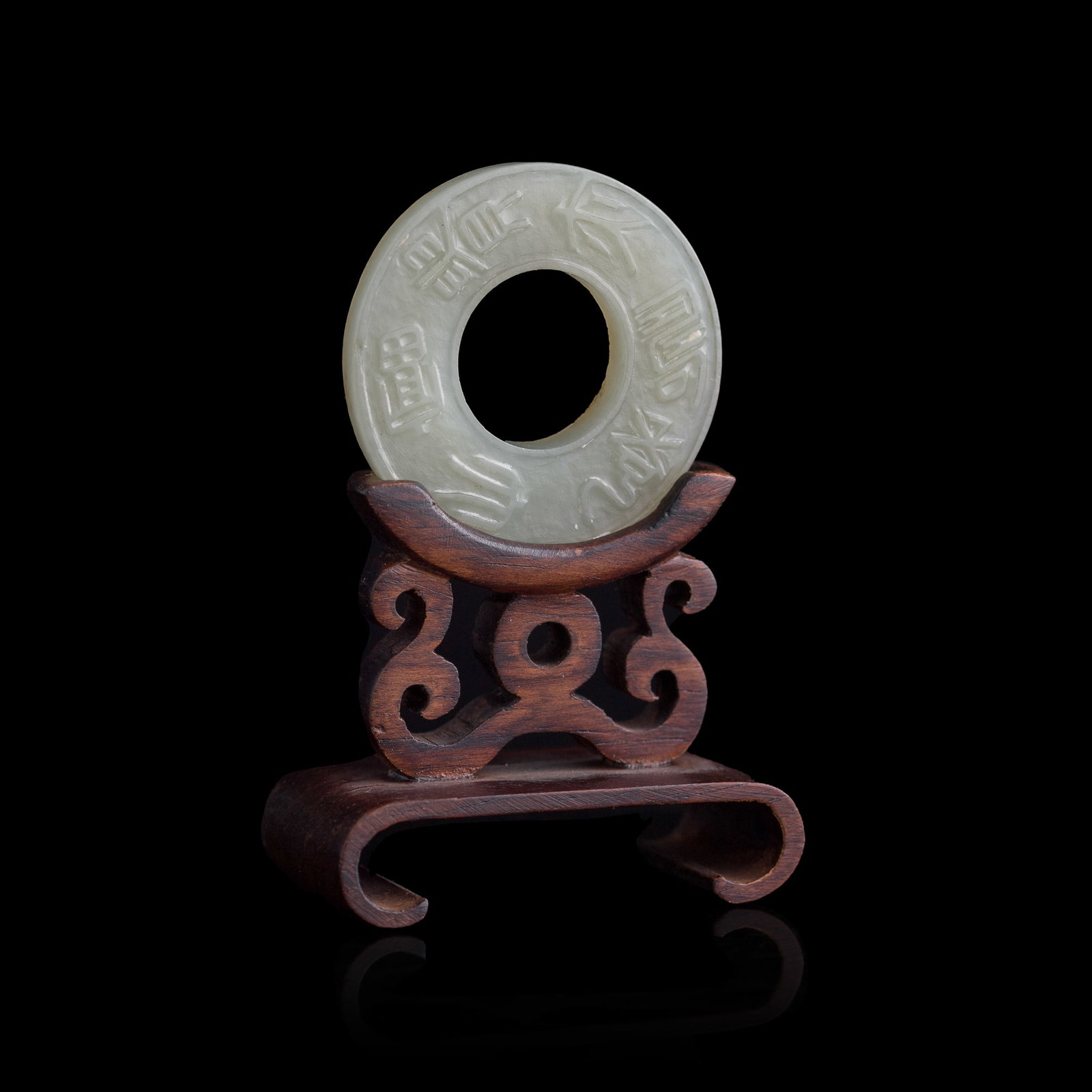 A Chinese white jade 'seal script' ring, 19th century: A Chinese white jade 'seal script' ring 19th century Sold with associated wooden stand. Ext. Dia: 38.4, Int. Dia: 17.5, D: 4.6 mm (ring) Private collection, Flushing, New York.