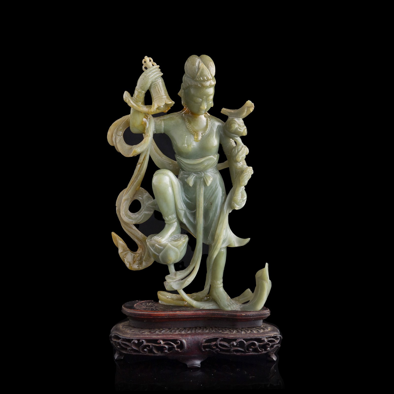 A Chinese jade carving of a flying apsara musician, Republic period: A Chinese jade carving of a flying apsara musician Republic period Sold with associated wooden stand. H: 7, W: 4 1/4, D: 1 1/4 in. (H: 17.8, W: 10.8, D: 3.2 cm. (jade)) Private collection, Florida.