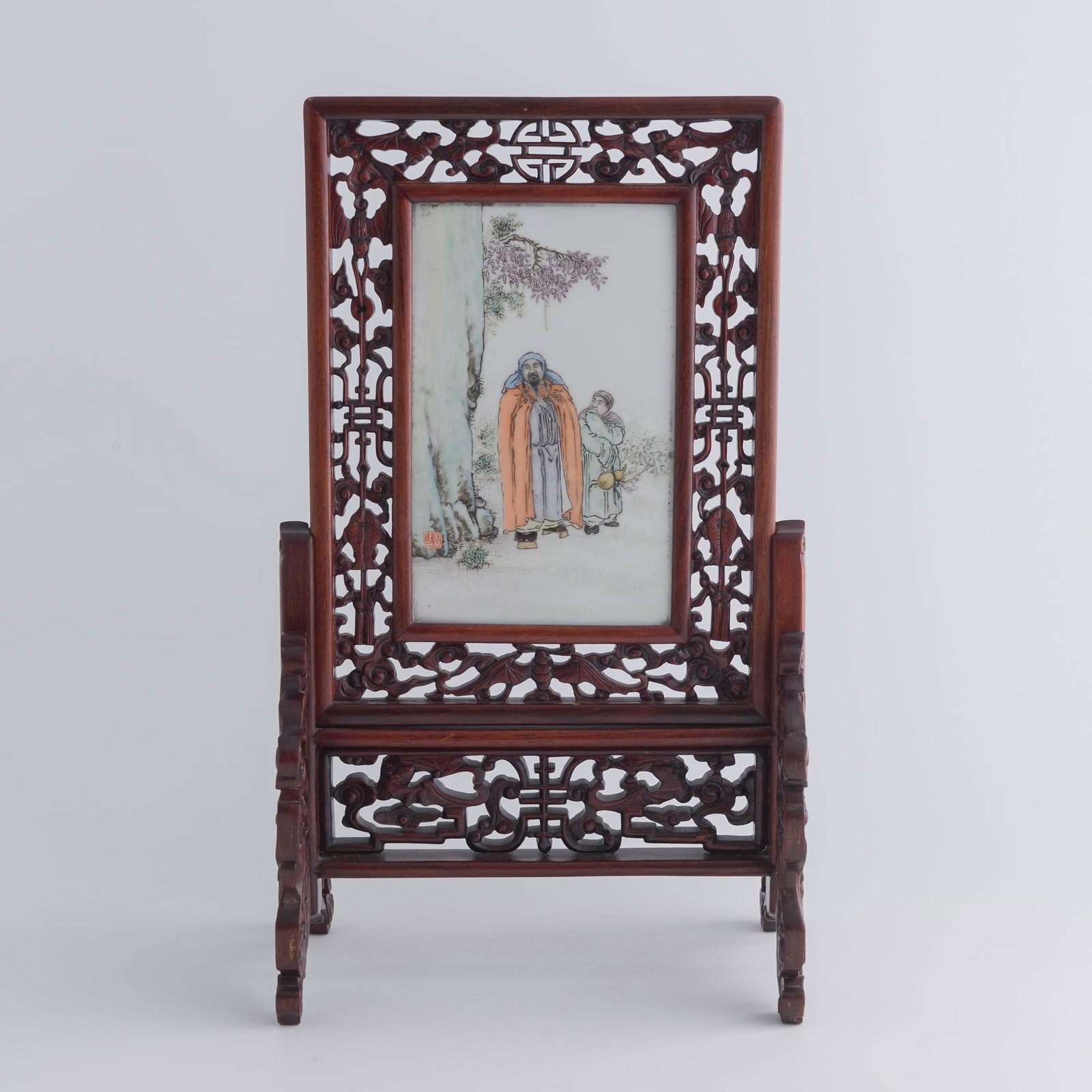 A Chinese famille rose porcelain plaque, by Liu Xiren, Republic period: A Chinese famille rose porcelain plaque by Liu Xiren, Republic period Painted with a standing scholar in orange robe accompanied by an attendant holding a gourd, set beside a tree in a tranquil landsc