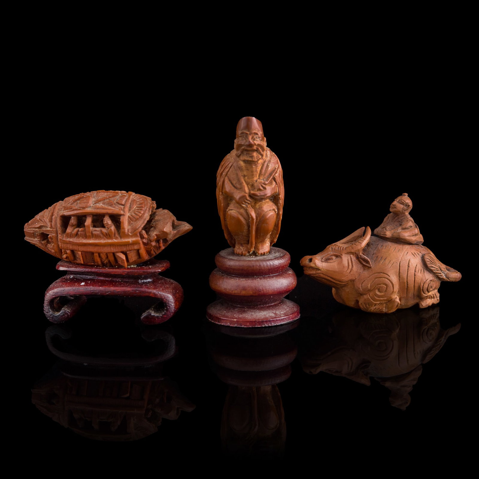 Three Chinese olive pit carvings, Republic period: Three Chinese olive pit carvings Republic period Sold with two associated wooden stands. (3). H: 1, W: 1 5/8, D: 3/4 in. (H: 2.5, W: 4.1, D: 1.9 cm. (pit, largest)) Private collection, Florida.