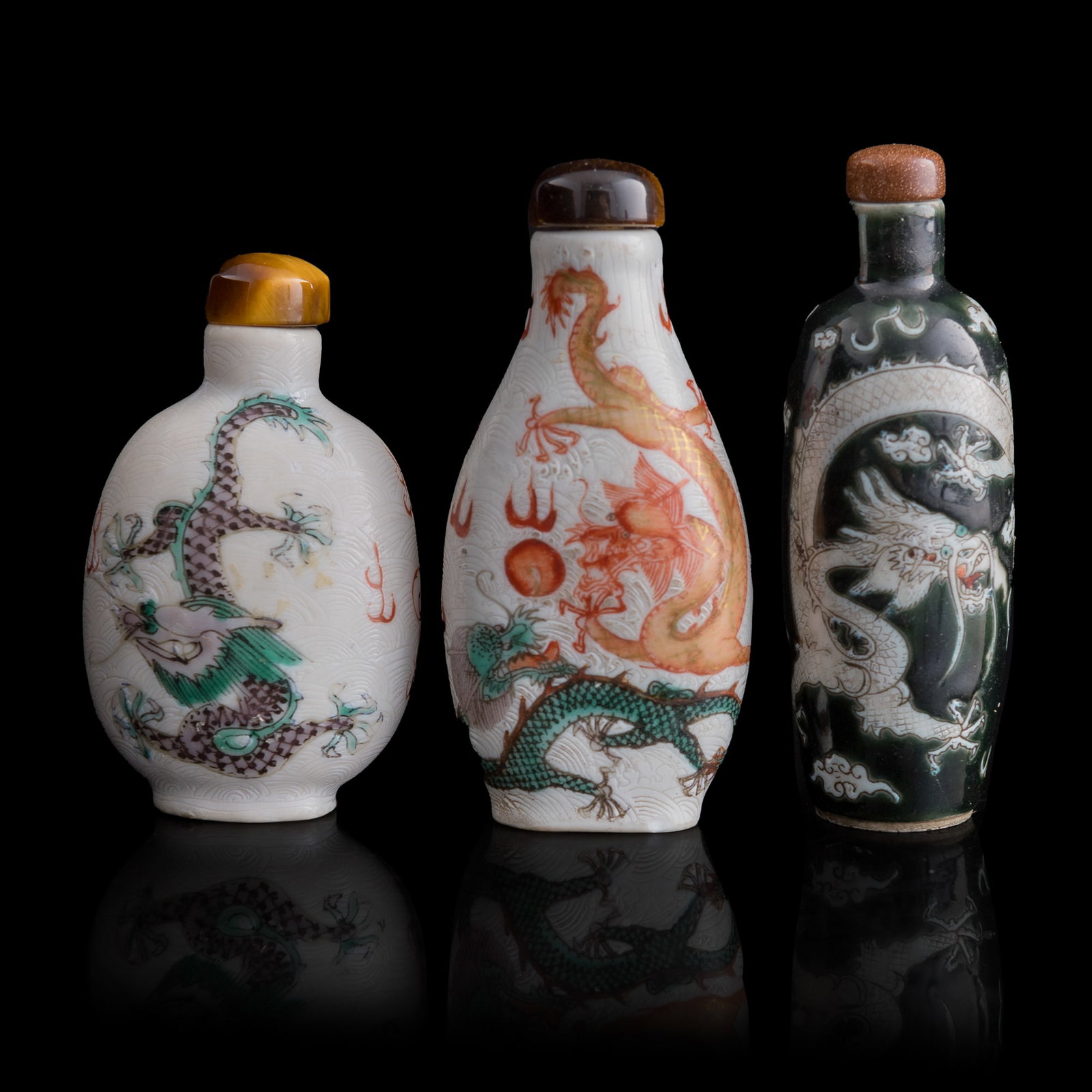 Three Chinese famille rose ‘dragon’ snuff bottles, 19th century: Three Chinese famille rose ‘dragon’ snuff bottles 19th century Two with four-character marks to the undersides. (3). H: 3 1/4, Dia: 1 1/8 in. (H: 8.3, Dia: 2.9 cm. (black-glazed)) From Mr. Tinero,