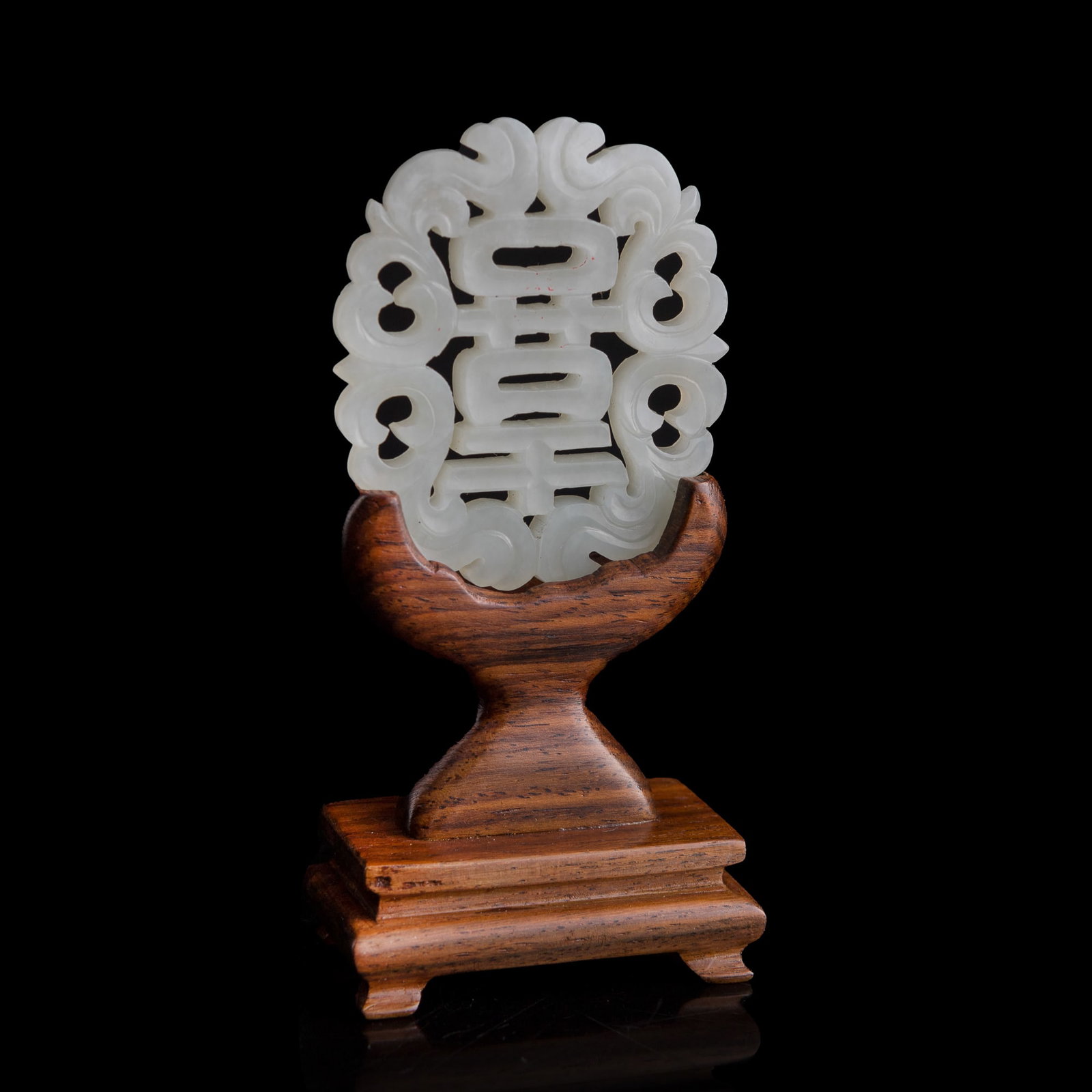 A Chinese reticulated white jade 'happiness' plaque, early 19th century: A Chinese reticulated white jade 'happiness' plaque early 19th century Sold with associated wooden stand. H: 2 3/8, W: 2, D: 1/8 in. (H: 6, W: 5.1, D: 0.3 cm. (jade)) From Mr. Tinero, Calabasas,