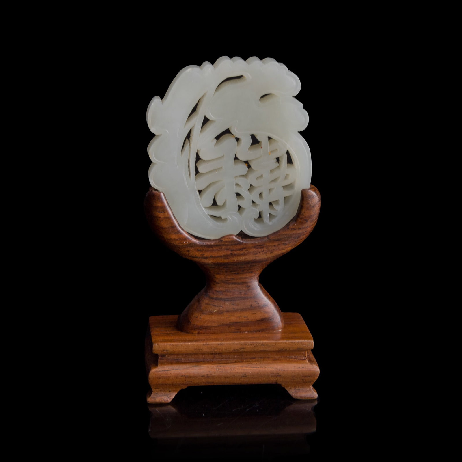 A Chinese carved white jade 'longevity' pendant, early 19th century: A Chinese carved white jade 'longevity' pendant early 19th century Sold with associated wooden stand. H: 2 1/8, W: 1 7/8, D: 1/4 in. (H: 5.4, W: 4.8, D: 0.6 cm. (jade)) From Mr. Tinero, Calabasas,