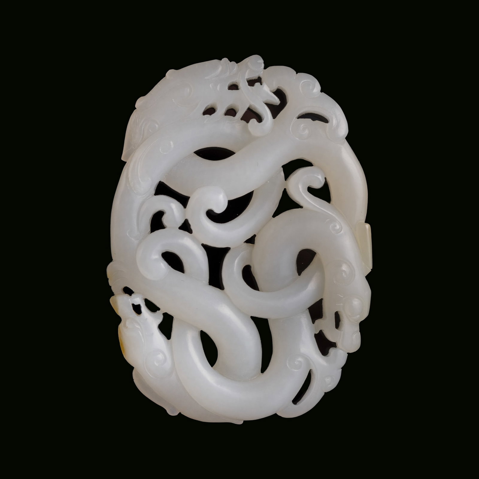 A Chinese carved white jade pendant of coiled dragons, 18th century: A Chinese carved white jade pendant of coiled dragons 18th century H: 2, W: 2 3/4, D: 3/8 in. (H: 5.1, W: 7, D: 1 cm.) From Mrs. Kiang in Newport Coast, California; collected by her late husband.