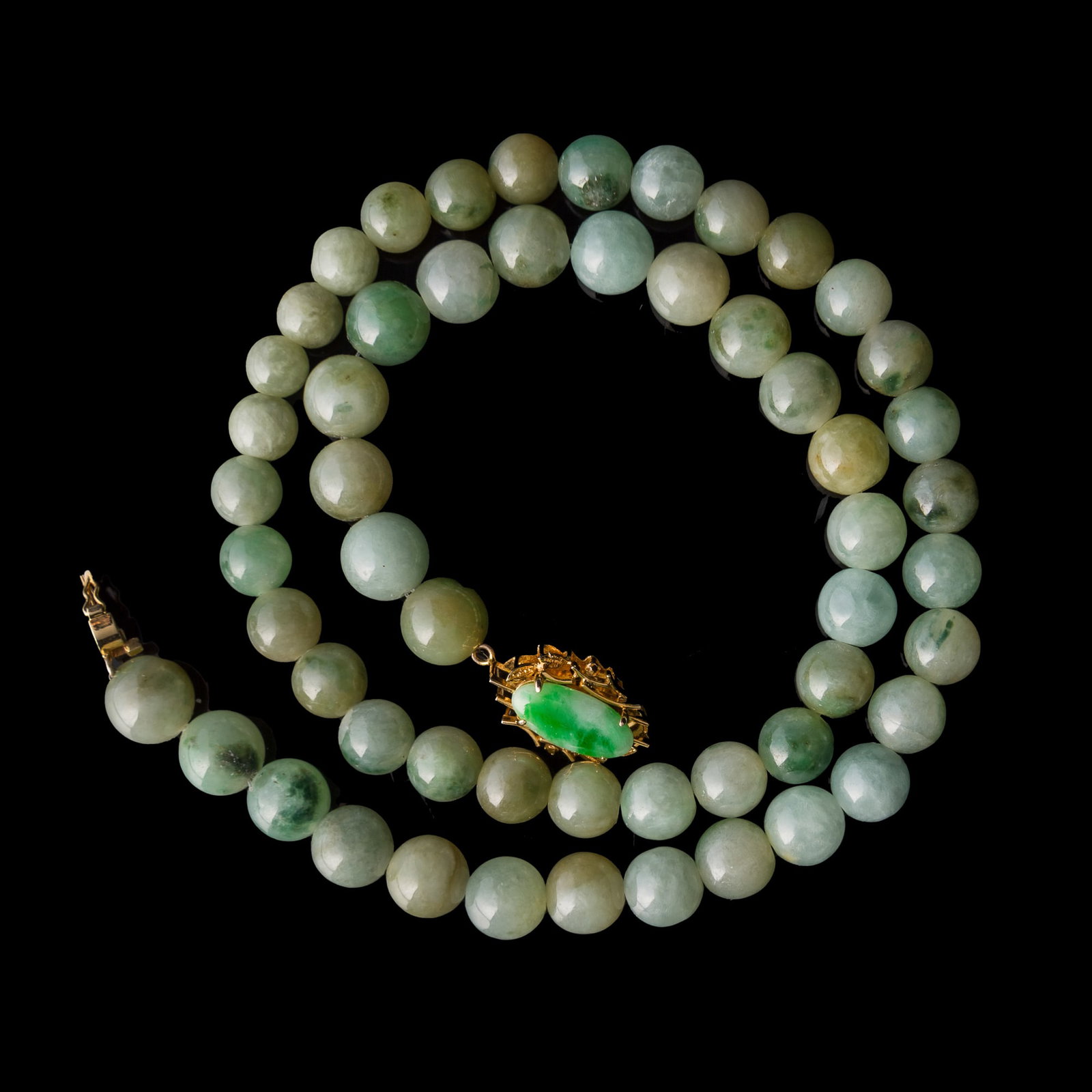 A Chinese jadeite bead necklace: A Chinese jadeite bead necklace With "585" stamp mark to clasp. L: 9 in. (22.9 cm.) Bead Dia.: 9.9 mm (largest) From Mrs. Ong in Huntington Beach, California.