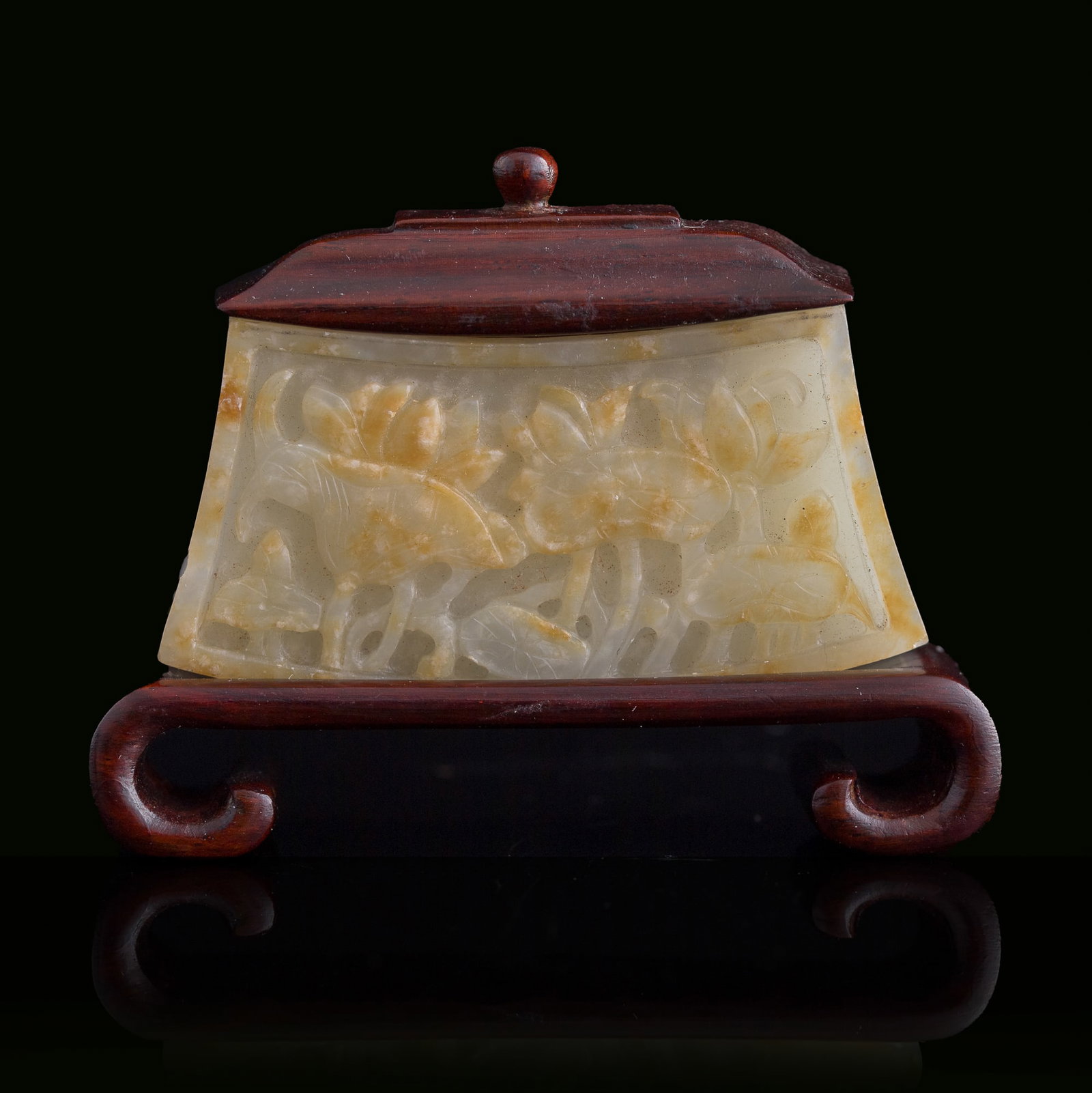 A Chinese carved jade 'lotus pond' fitting, Ming dynasty: A Chinese carved jade 'lotus pond' fitting Ming dynasty Possibly from the terminal of a ruyi. Sold with associated wooden lid and stand. H: 1 3/8, W: 2 1/2, D: 5/8 in. (H: 3.5, W: 6.4, D: 1.6 cm. (jad