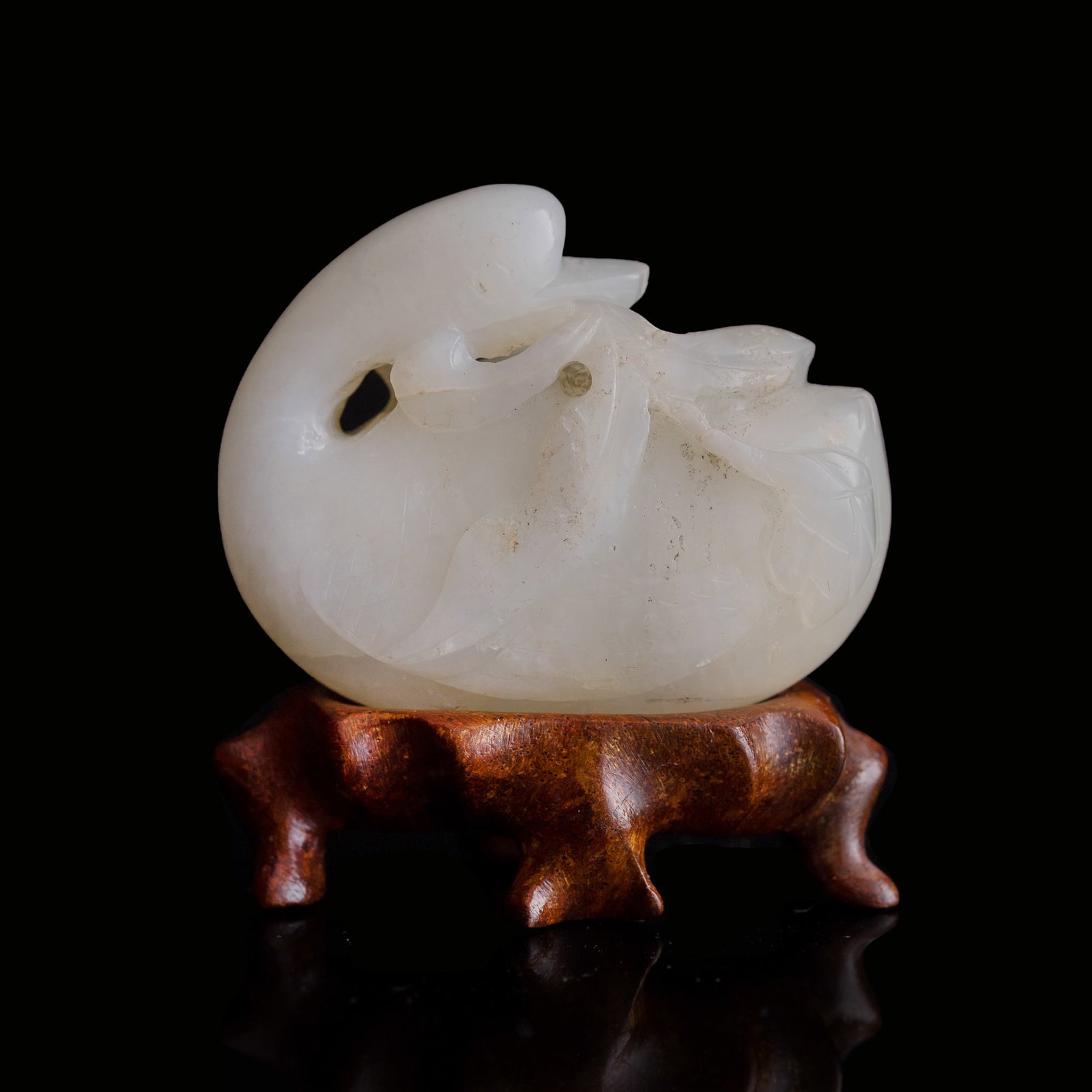 A Chinese white jade pendant of a goose, 19th century: A Chinese white jade pendant of a goose 19th century Sold with associated wooden stand. H: 1 1/2, W: 1 7/8, D: 1 in. (H: 3.8, W: 4.8, D: 2.5 cm. (jade)) From Mr. Gable in Rockville, Maryland.