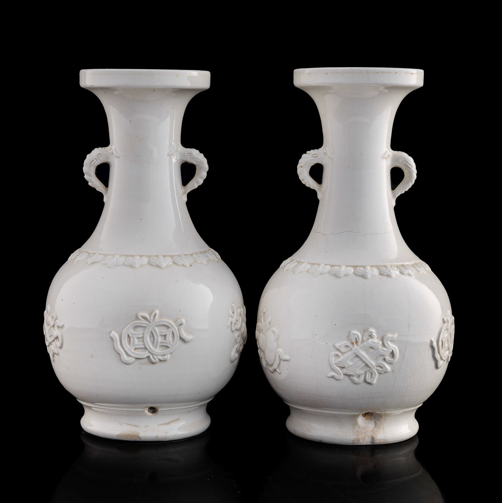 A pair of Chinese blanc-de-chine double-handled vases, 19th century: A pair of Chinese blanc-de-chine double-handled vases 19th century Each with 'Eight Daoist Emblems' carving to body. (2). H: 12 1/8, Dia: 6 7/8 in. (H: 30.8, Dia: 17.5 cm. (each)) Private collection, 