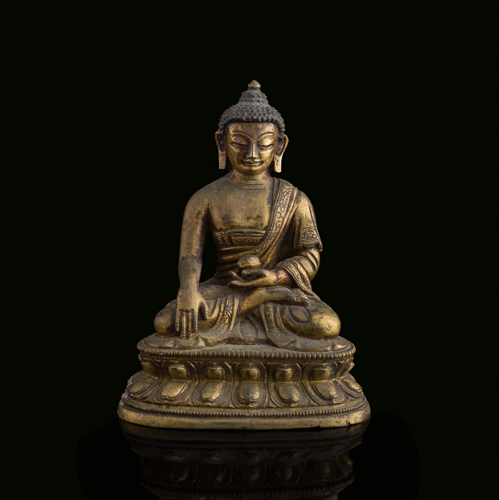 A Chinese gilt-bronze figure of Shakyamuni attaining enlightenment, 18th century: A Chinese gilt-bronze figure of Shakyamuni attaining enlightenment 18th century Incised with a stylized floral medallion to underside. H: 4 1/4, W: 3 3/8, D: 2 1/4 in. (H: 10.8, W: 8.6, D: 5.7 cm.) We