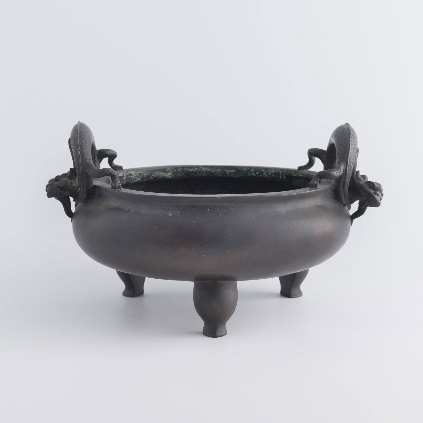 A Chinese bronze tripod censer with double dragon handles, 19th century: A Chinese bronze tripod censer with double dragon handles 19th century With sixteen-character mark to underside. Accompanied by a Christie's tag. H: 6 1/2, W: 11 5/8, D: 9 1/2 in. (H: 16.5, W: 29.5, D