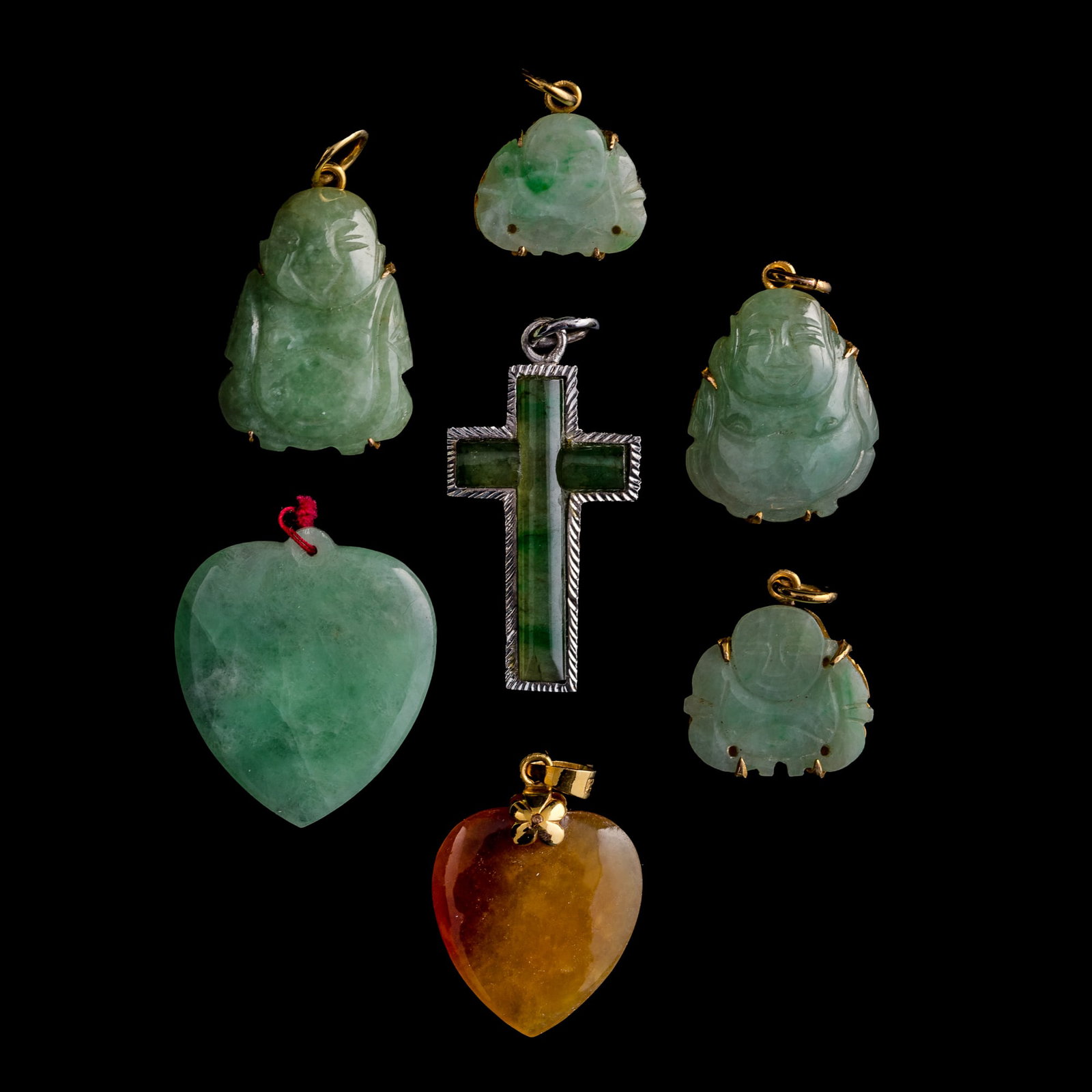 Seven assorted jadeite pendants: Seven assorted jadeite pendants Comprising a cross pendant, marked "K Baijin" (karat white gold) to the reverse; four Buddha pendants, three marked "14K" to the reverse; and two heart-shaped pendants,