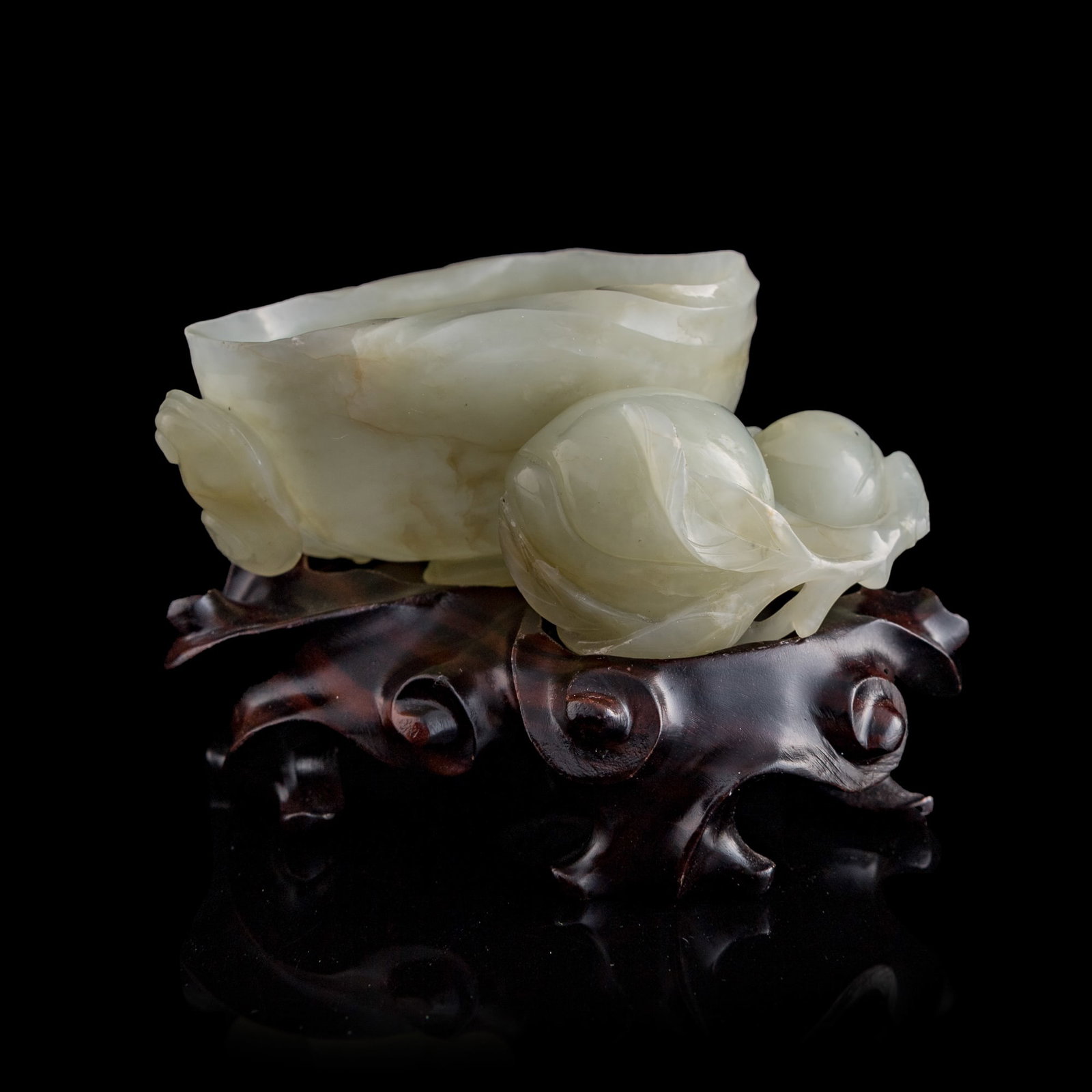 A Chinese white jade peach-form water coupe, 18th century: A Chinese white jade peach-form water coupe 18th century Sold with an associated wooden stand, bearing a collection label from The Jade Dragon, an antique shop in Ann Arbor, Michigan, numbered 15468. 