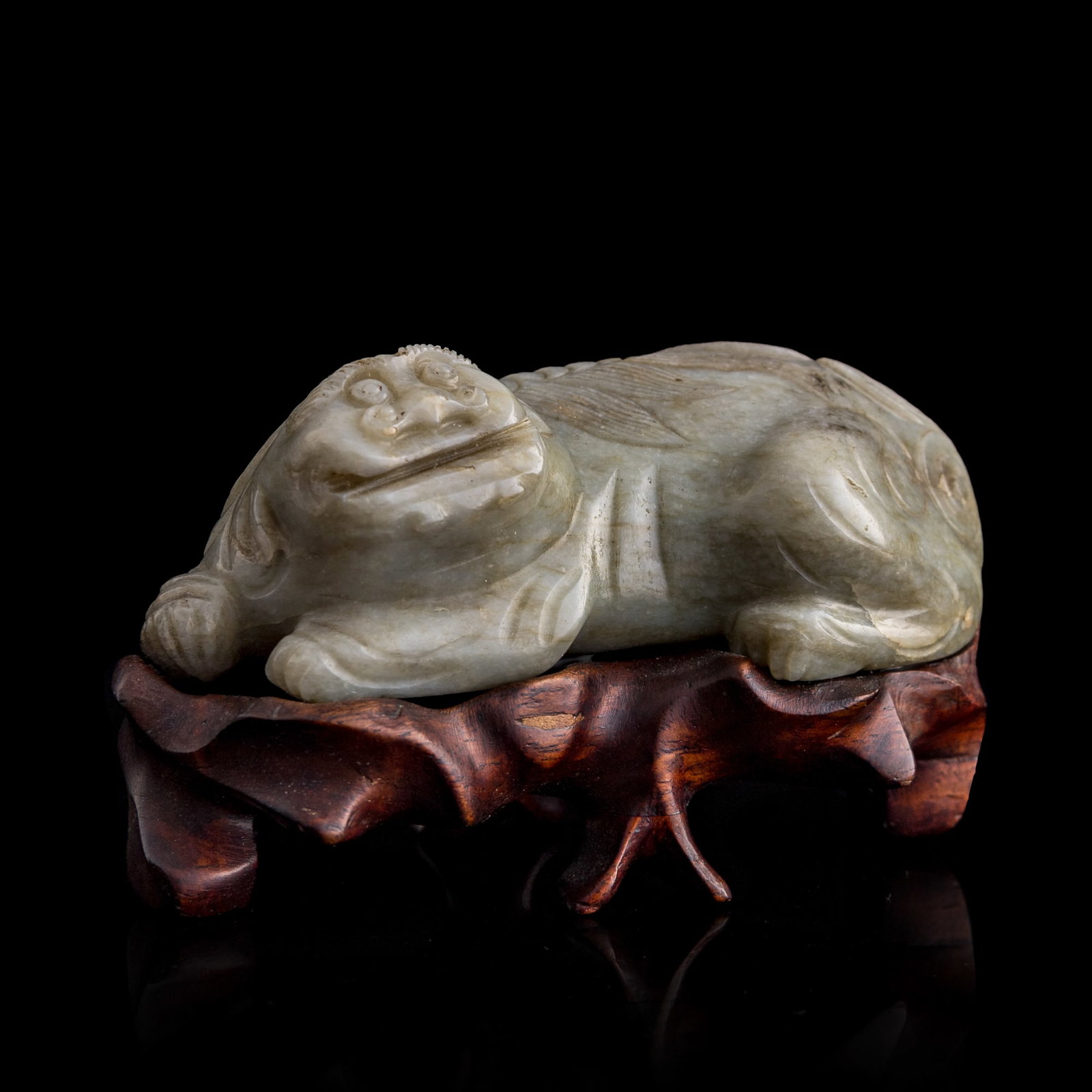 A Chinese jade mythical beast, Ming dynasty: A Chinese jade mythical beast Ming dynasty Sold with associated hardwood stand. H: 1 1/2, W: 4, D: 1 7/8 in. (H: 3.8, W: 10.2, D: 4.8 cm. (jade)) Private collection, Charlottesville, Virginia.