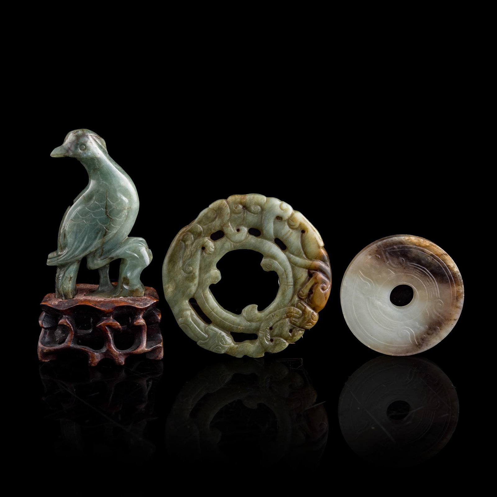 Two Chinese jade bi discs and a jadeite bird, Ming/Qing dynasty: Two Chinese jade bi discs and a jadeite bird Ming/Qing dynasty Sold with one associated wooden stand. (3). Bird: H: 3, W: 1 3/4, D: 1/2 in. (H: 7.6, W: 4.4, D: 1.3 cm.) Largest bi disc: Outer Dia: 71.