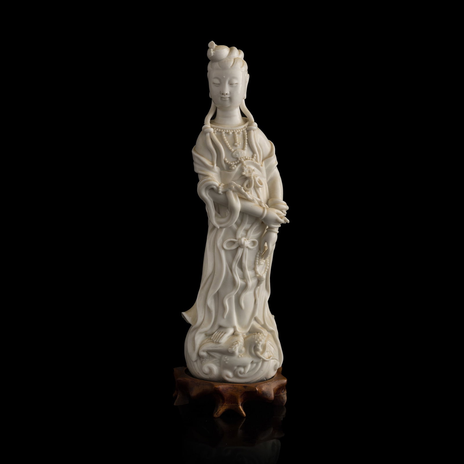 A Chinese Dehua figure of Guanyin, 19th century: A Chinese Dehua figure of Guanyin 19th century With two marks to the back, one reads Xuande. Sold with original fitted brocade box and a stand. Also accompanied by an old note, possibly written by its