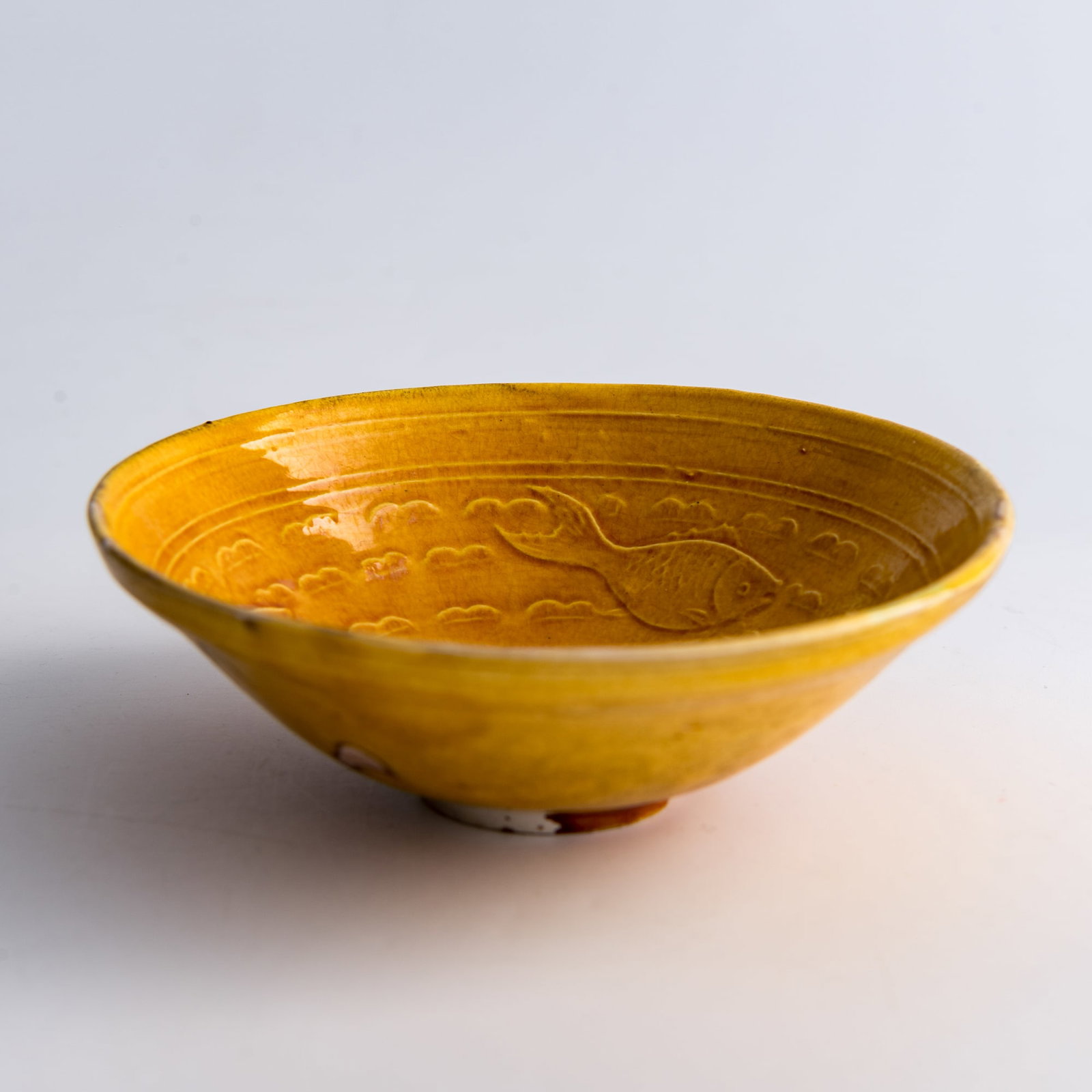 A Chinese yellow-ground molded 'three fish' bowl, the Liao and Jin/Song dynasty: A Chinese yellow-ground molded 'three fish' bowl the Liao and Jin/Song dynasty H: 1 1/2, Dia: 4 1/2 in. (H: 3.8, Dia: 11.4 cm.) Private collection, Palo Alto, California.