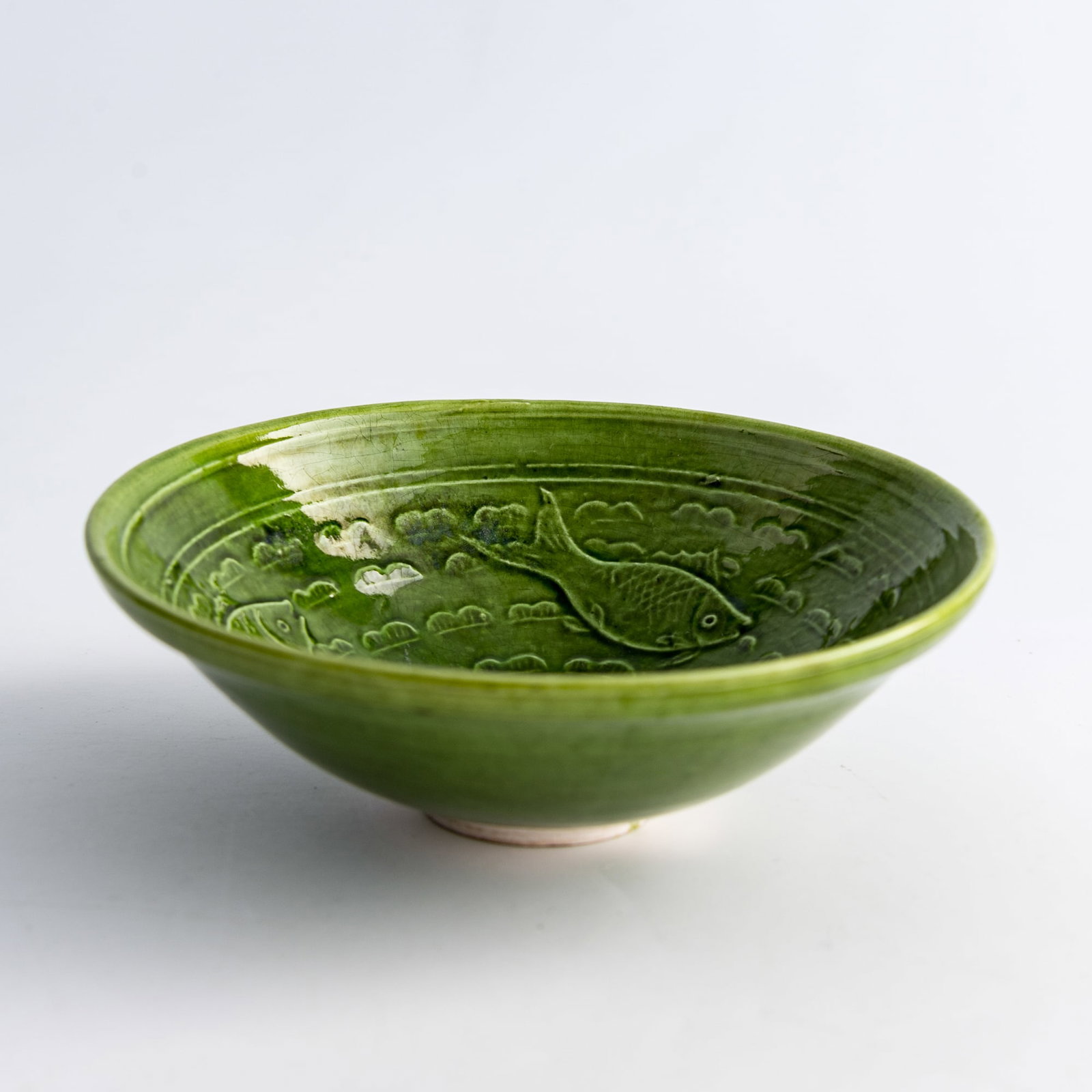 A Chinese green-glazed molded 'three fish' bowl, the Liao and Jin/Song dynasty (1 of 8)