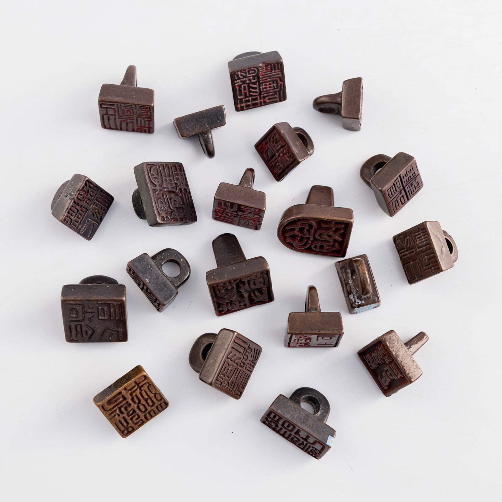 Twenty Chinese bronze seals with nose-form finials, Ming/Qing dynasty: Twenty Chinese bronze seals with nose-form finials Ming/Qing dynasty Three with six-character mark, two with two-character mark, and fifteen with four-character mark to underside. (20). H: 1 1/4, W: 1