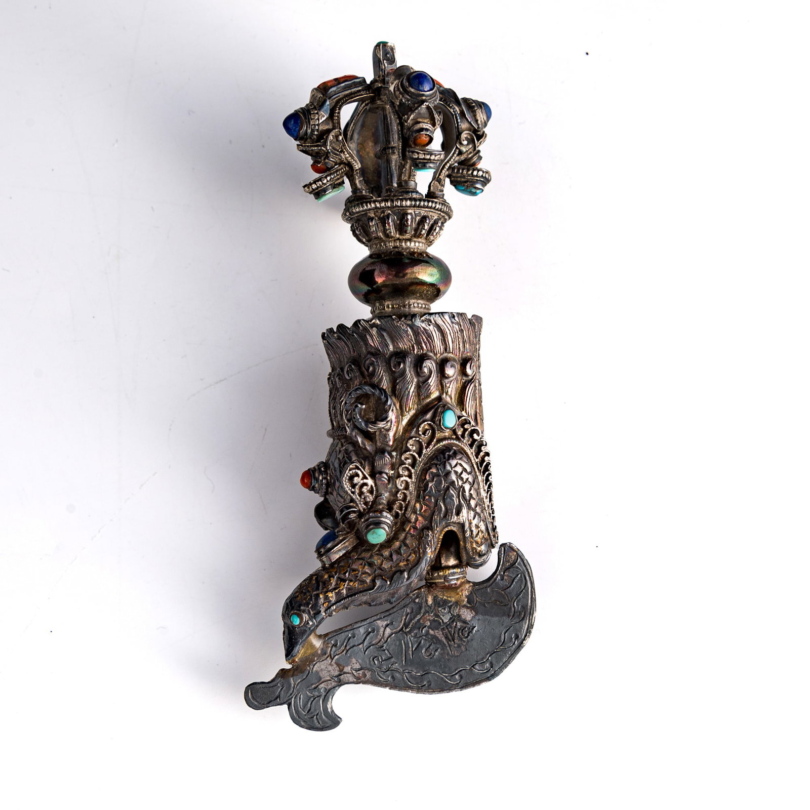 A Tibetan silver hardstone-inlaid makara-form vajra, 19th century: A Tibetan silver hardstone-inlaid makara-form vajra 19th century H: 6, W: 2 3/4, D: 2 in. (H: 15.2, W: 7, D: 5.1 cm.) Weight: 115 g Private collection, Charlottesville, Virginia. Click here for high
