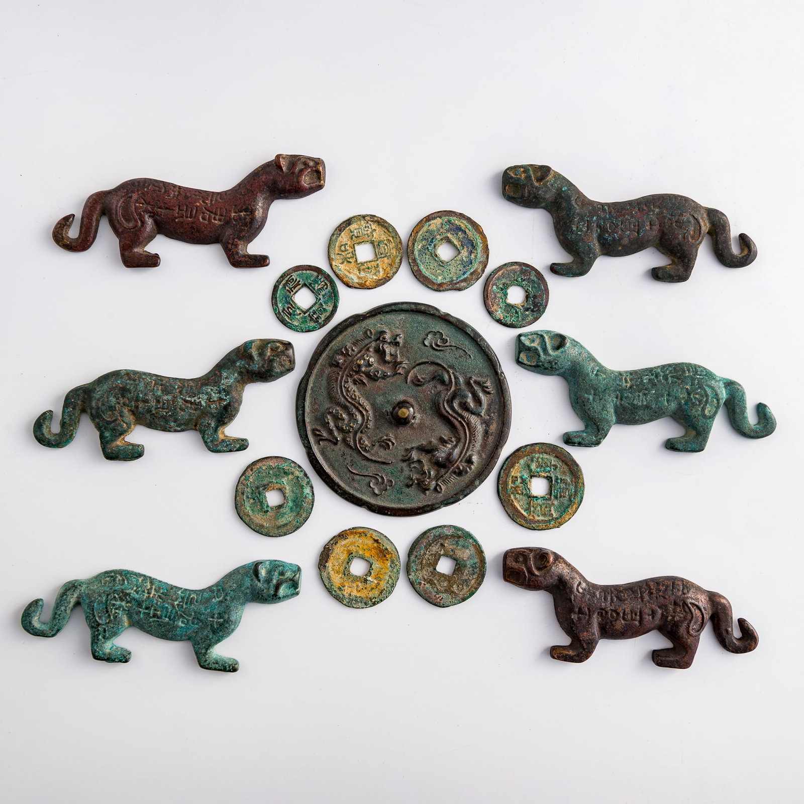 A group of Chinese bronze tiger tallies, coins, and a mirror, Han dynasty or later: A group of Chinese bronze tiger tallies, coins, and a mirror Han dynasty or later Comprising three pairs of bronze tiger-form tallies, a bronze mirror, and eight bronze coins. (15). H: 1/8, Dia: 3