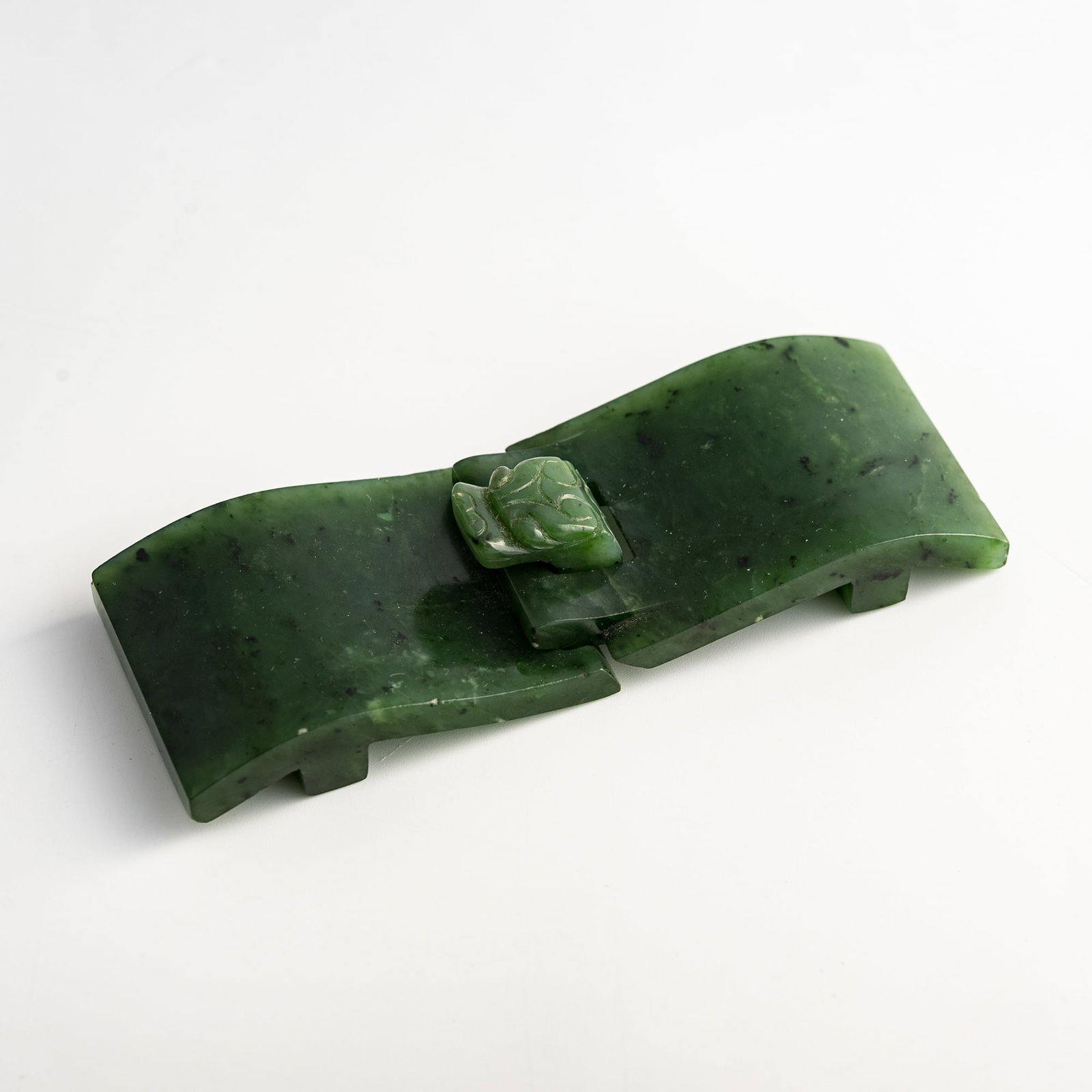 A Chinese spinach jade belt buckle, 18th century: A Chinese spinach jade belt buckle 18th century H: 1 5/8, W: 4 5/8, D: 7/8 in. (H: 4.1, W: 11.7, D: 2.2 cm.) Private collection, Lovettsville, Virginia. Cli