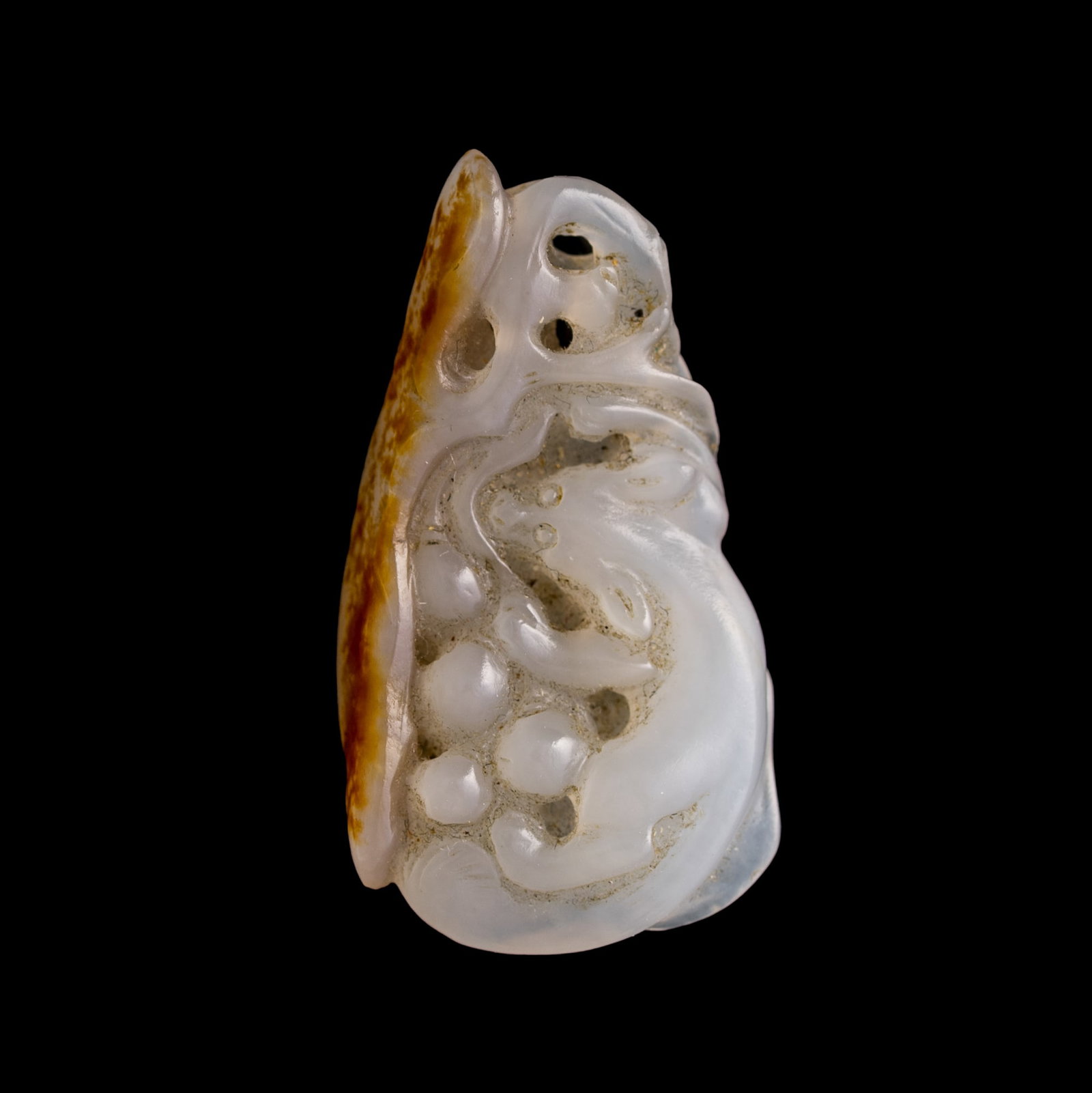 A Chinese white jade 'squirrel and grape' pendant with russet skin, early 19th century: A Chinese white jade 'squirrel and grape' pendant with russet skin early 19th century H: 1 1/2, W: 7/8, D: 1/4 in. (H: 3.8, W: 2.2, D: 0.6 cm.) Private collection, New York. Click here for high