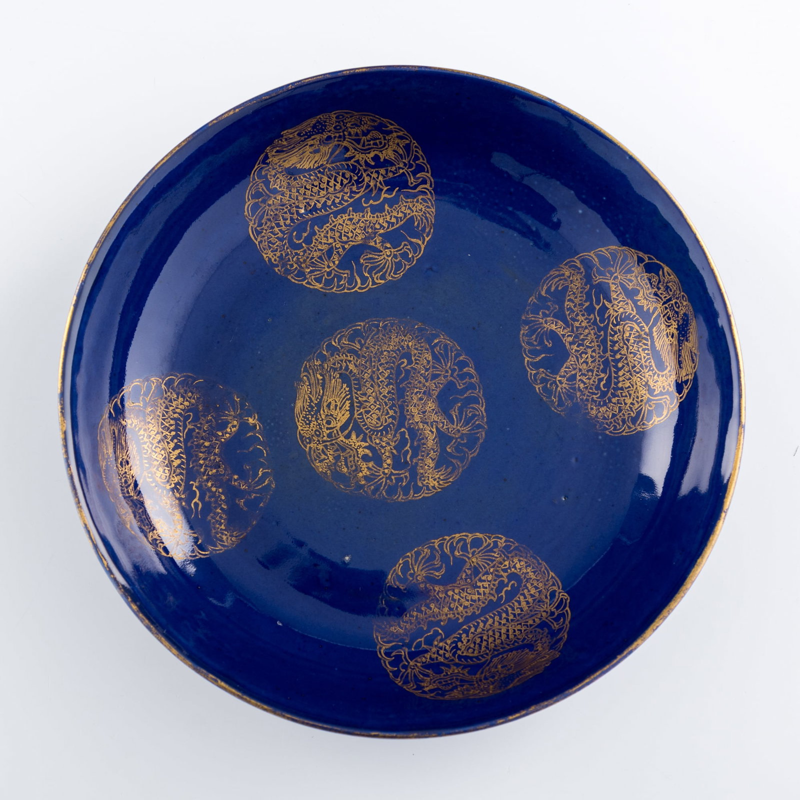A Chinese gilt-decorated sacrificial-blue-glazed dish, Guangxu period, Qing dynasty: A Chinese gilt-decorated sacrificial-blue-glazed dish Guangxu period, Qing dynasty Featuring five gilt 'dragon' medallions. With six-character Guangxu mark to underside. H: 1 1/4, Dia: 6 1/8 in. (H: 3