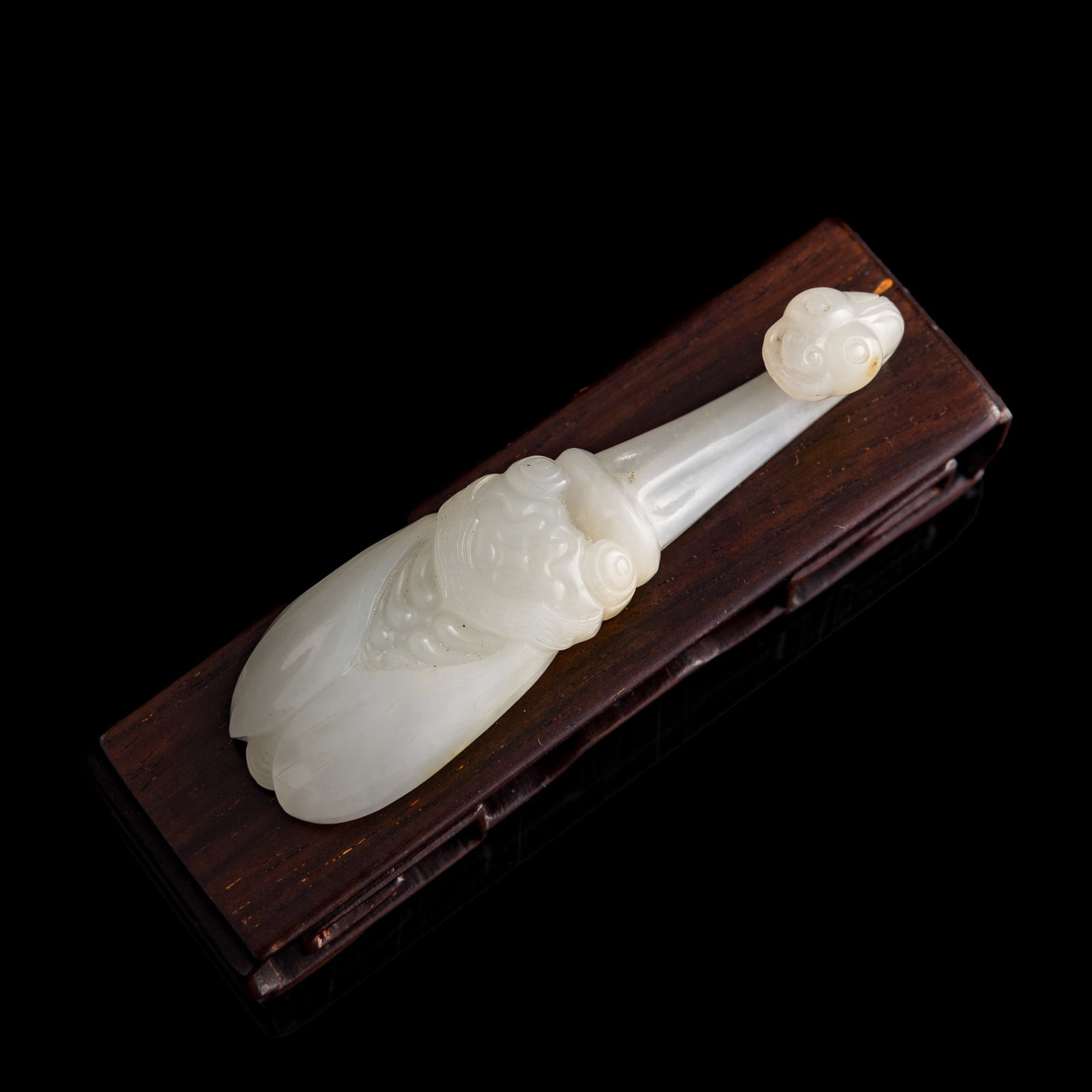 A Chinese white jade cicada-form belt hook, Qianlong period, Qing dynasty: A Chinese white jade cicada-form belt hook Qianlong period, Qing dynasty Sold with associated wooden stand. H: 5/8, W: 7/8, D: 3 1/8 in. (H: 1.6, W: 2.2, D: 7.9 cm. (belt hook)) From an estate in San