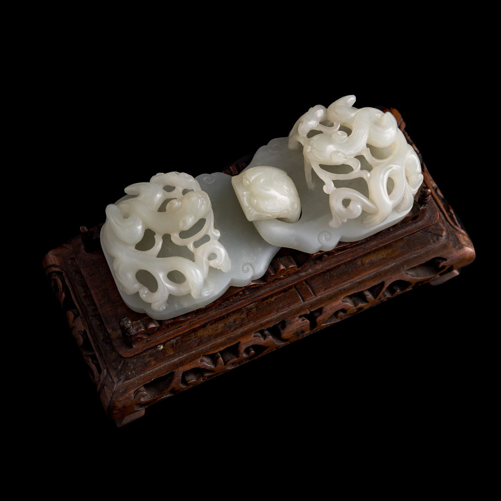 A Chinese white jade 'chilong' belt buckle, 18th century: A Chinese white jade 'chilong' belt buckle 18th century Sold with associated hardwood stand. H: 1, W: 4 1/4, D: 1 3/4 in. (H: 2.5, W: 10.8, D: 4.4 cm.) From an estate in San Diego, California. Click